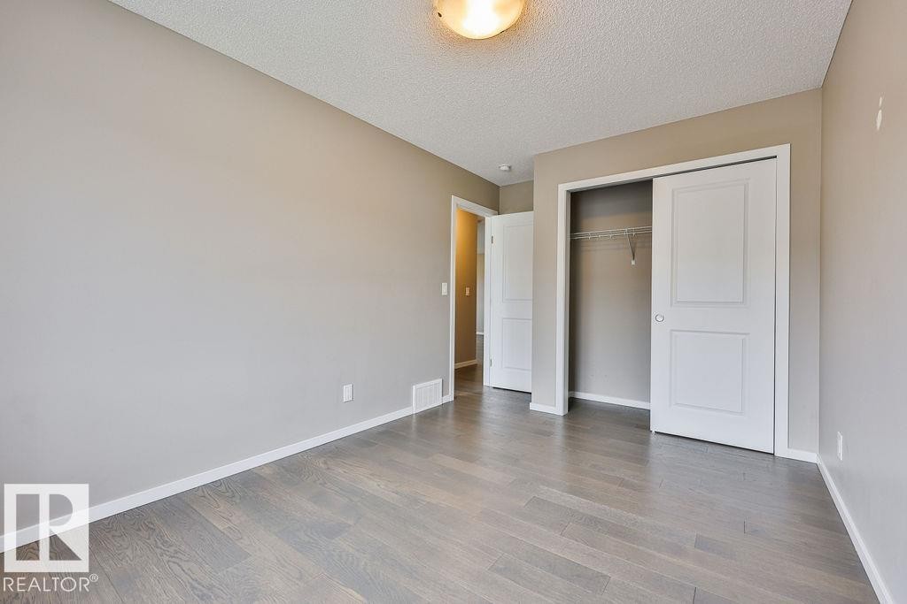 Room featuring wood-finish flooring, neutral wall paint, and white baseboards - 2031 207 Street, Edmonton, AB