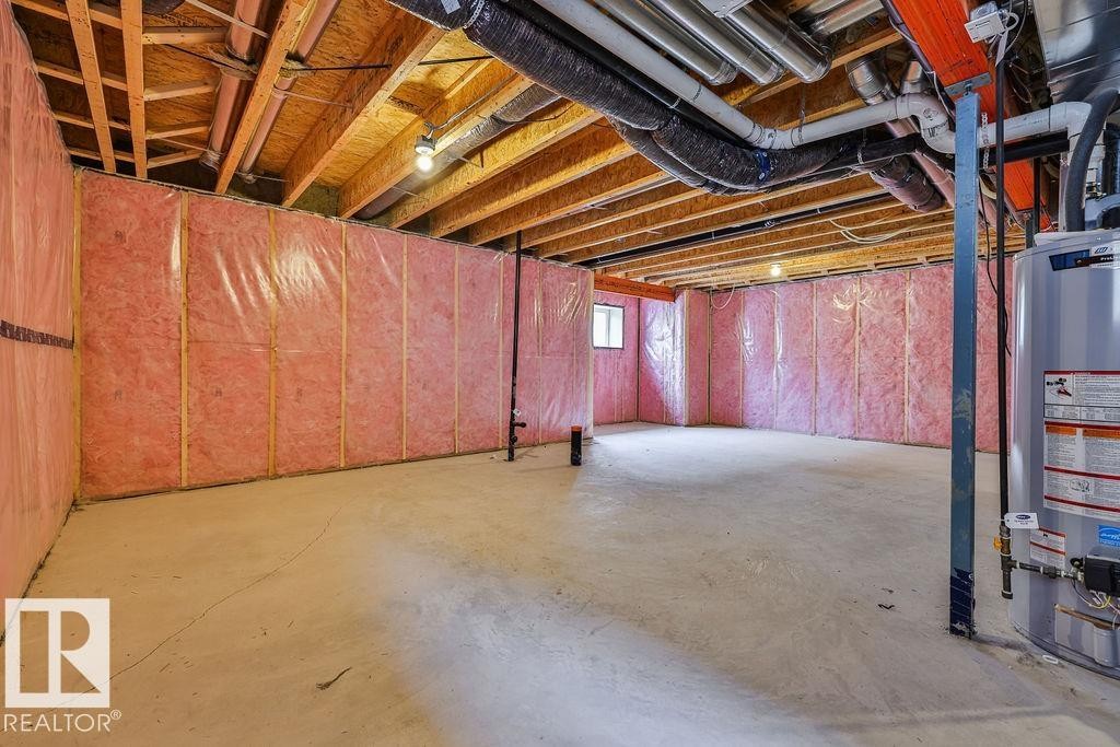Unfinished basement featuring exposed wood joists, concrete flooring, insulated perimeter walls, a utility window, and a water heater. Side Separate Entrance For Future Self-Contained Suite Potential. - 2031 207 Street, Edmonton, AB