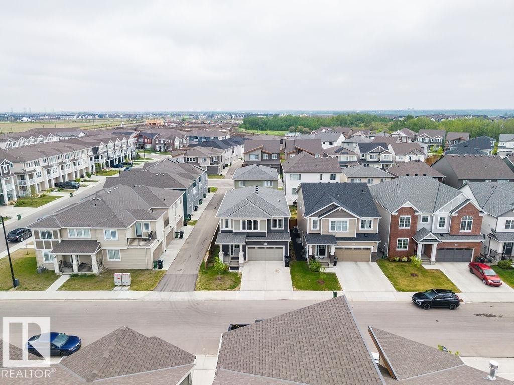 Aerial perspective showcasing a residential community with diverse architectural styles, featuring two-story homes with attached garages, shingled roofs, and varied exterior finishes including brick, siding, and stone accents - 2031 207 Street, Edmonton, AB