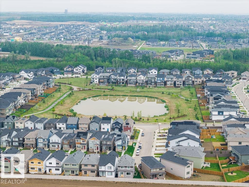 Modern residential development featuring a central pond, landscaped green spaces, and connecting pathways - 2031 207 Street, Edmonton, AB