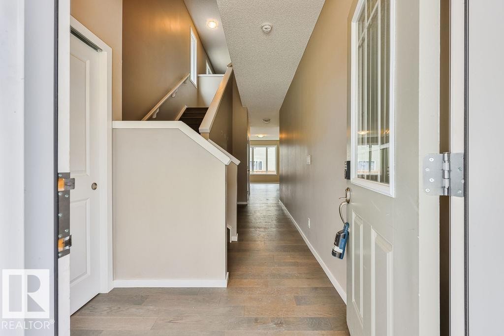 Entryway featuring wood-finish flooring, a contemporary staircase, recessed lighting, and a white paneled door with an integrated window - 2031 207 Street, Edmonton, AB