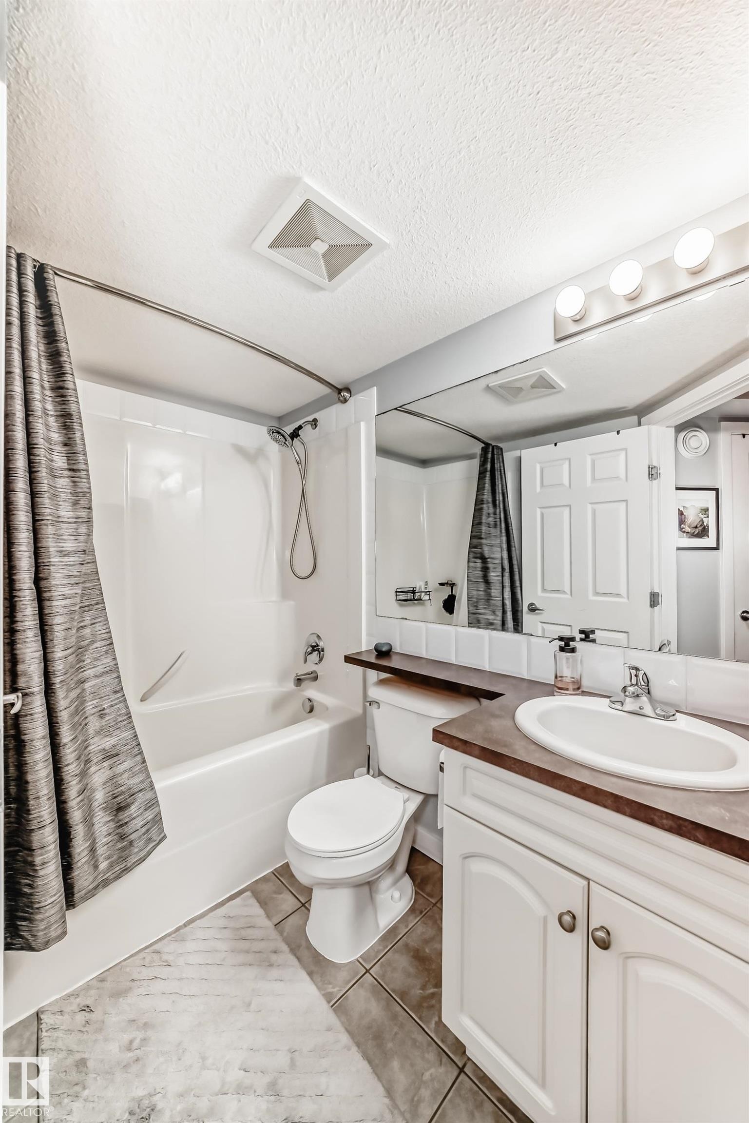 Bathroom featuring a white bathtub with shower, toilet, and vanity with an integrated sink - 53 150 Edwards Drive, Edmonton, AB