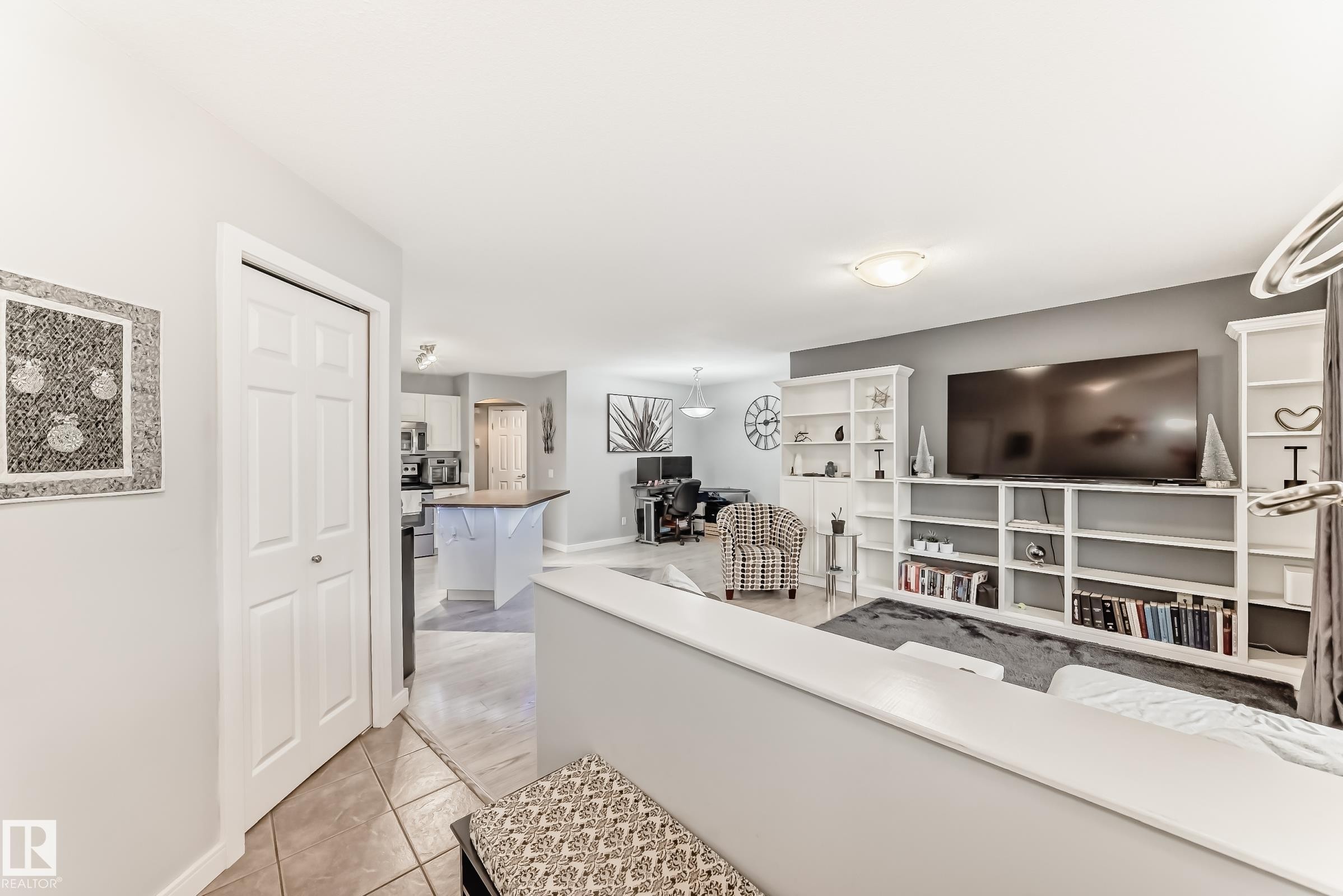 Open-concept living area featuring a built-in media center with extensive shelving, light gray wall paint, and recessed lighting - 53 150 Edwards Drive, Edmonton, AB