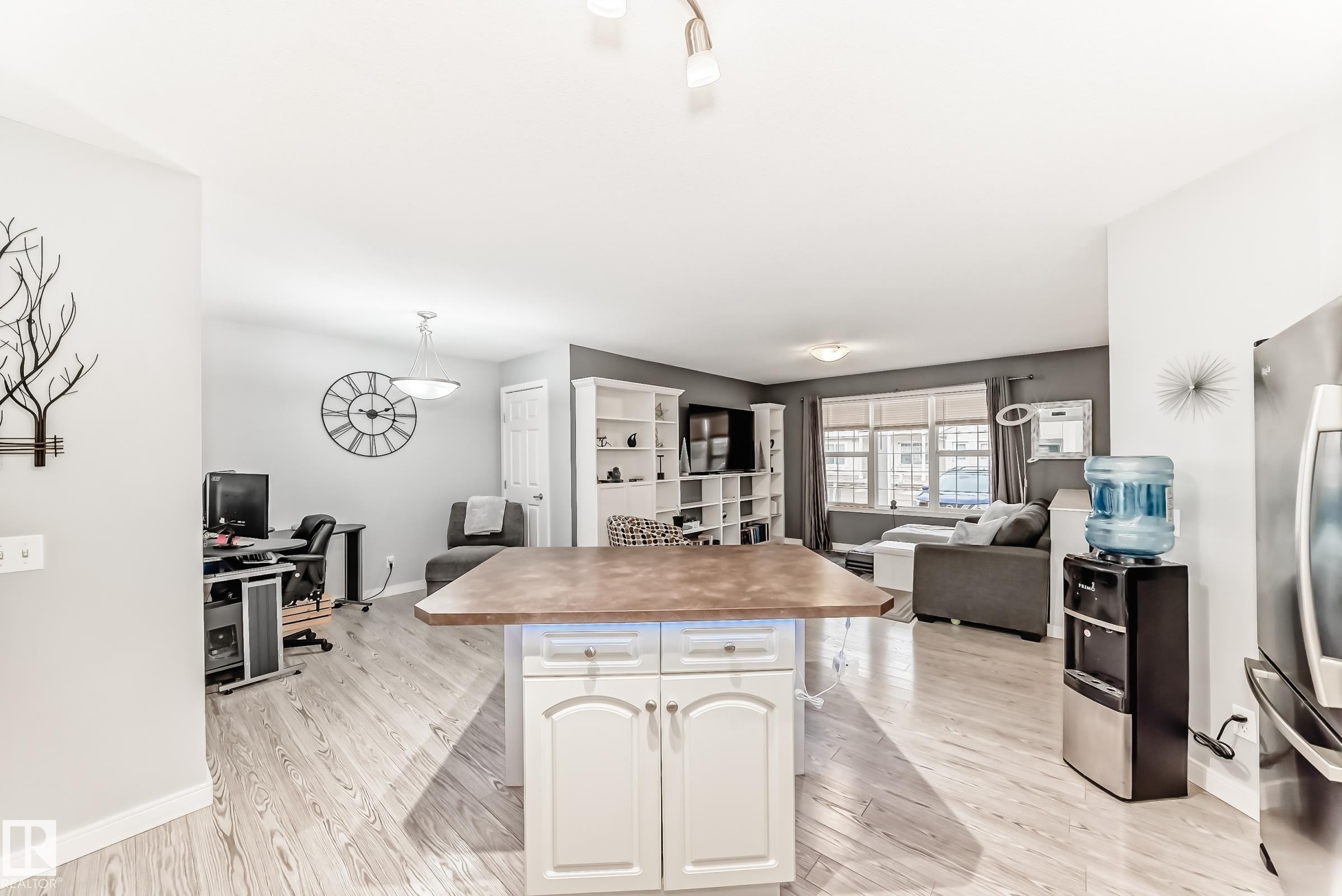 Open-concept interior featuring light wood-finish flooring, a kitchen island with white cabinetry, built-in shelving, and recessed lighting - 53 150 Edwards Drive, Edmonton, AB