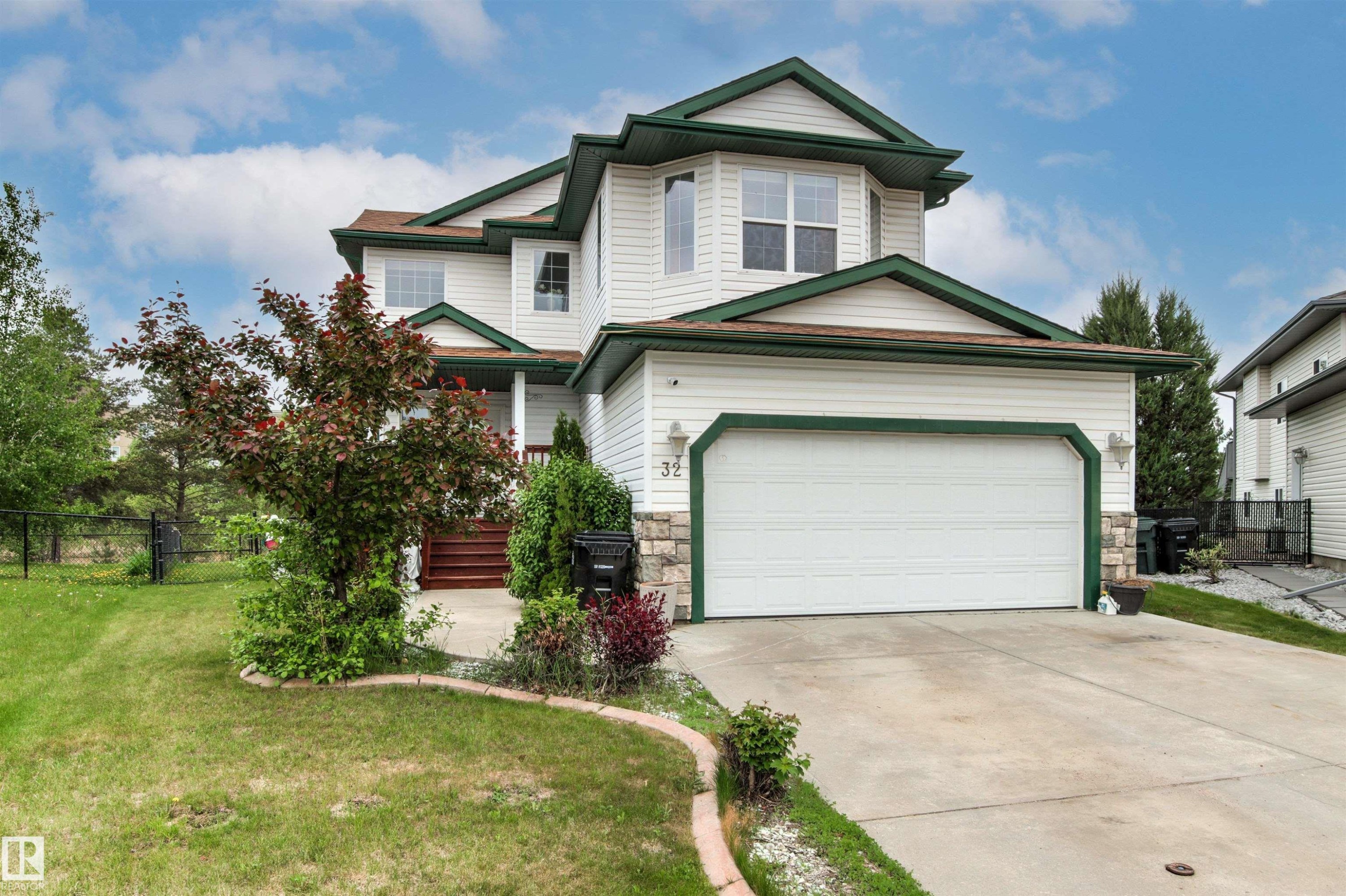 Two-story residence featuring white siding and green trim accents - 32 Lamplight Bay, Spruce Grove, AB