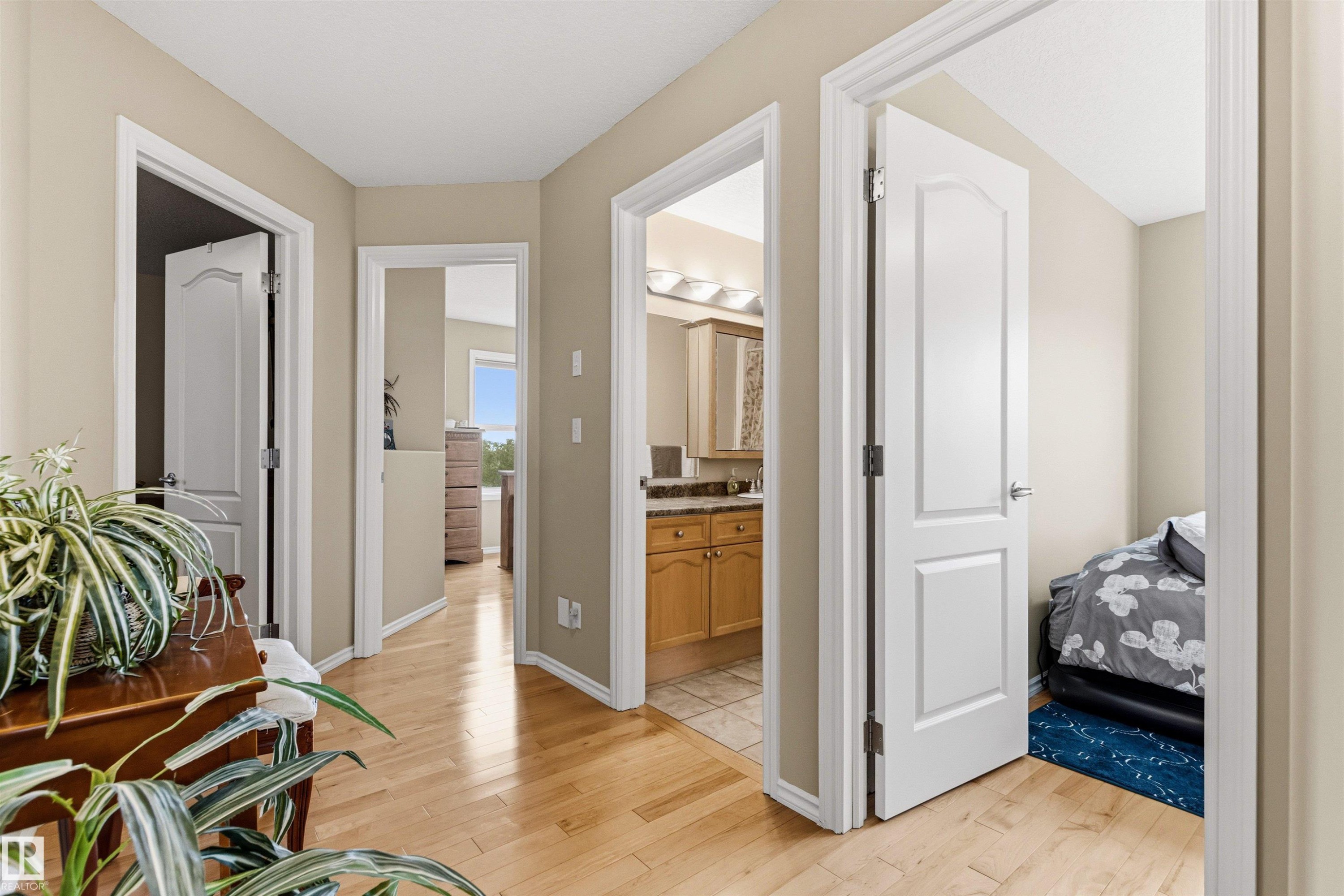 Hardwood flooring in a neutral-toned hallway with white trim and doors - 32 Lamplight Bay, Spruce Grove, AB