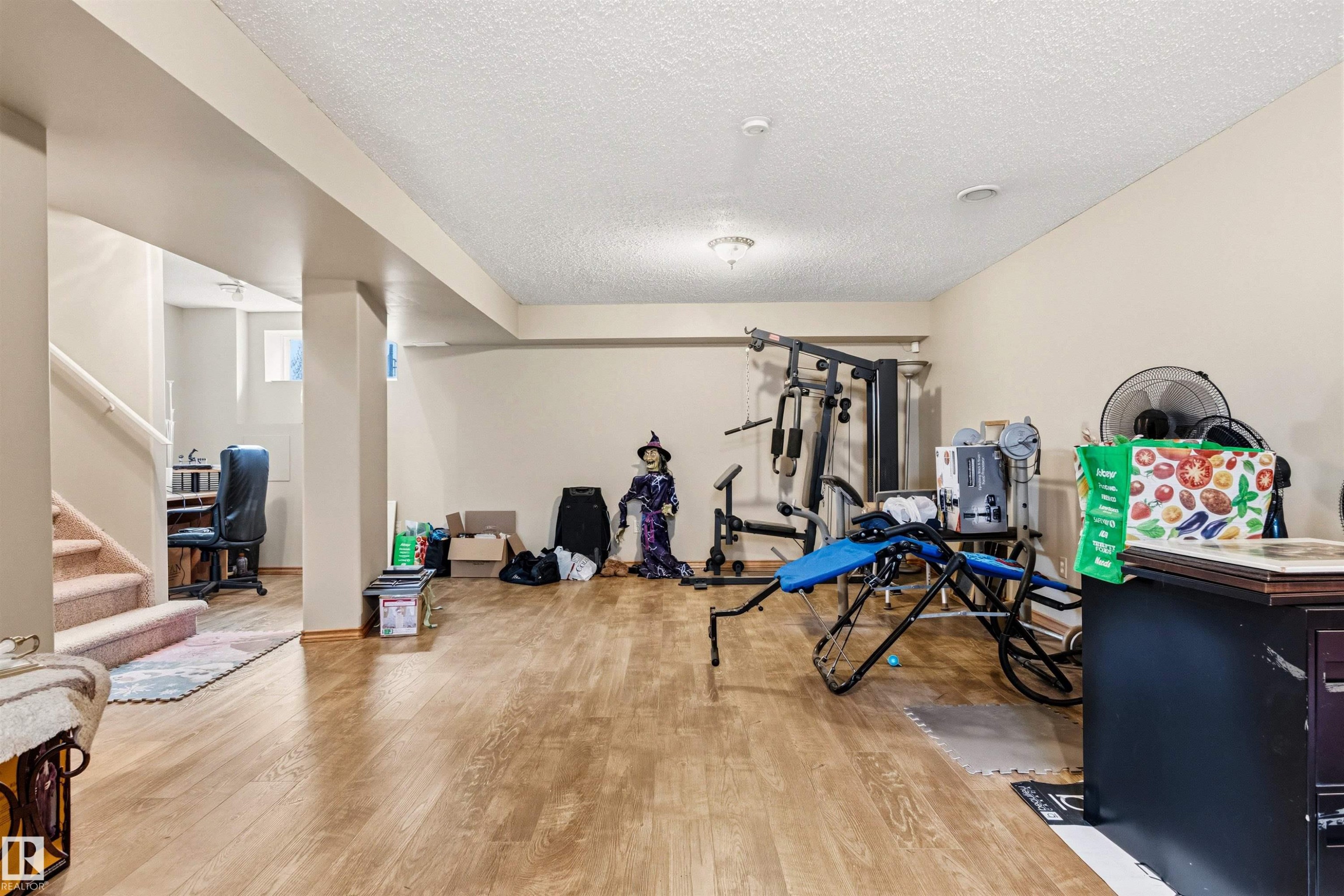 Spacious lower level featuring wood-finish flooring and neutral wall tones - 32 Lamplight Bay, Spruce Grove, AB