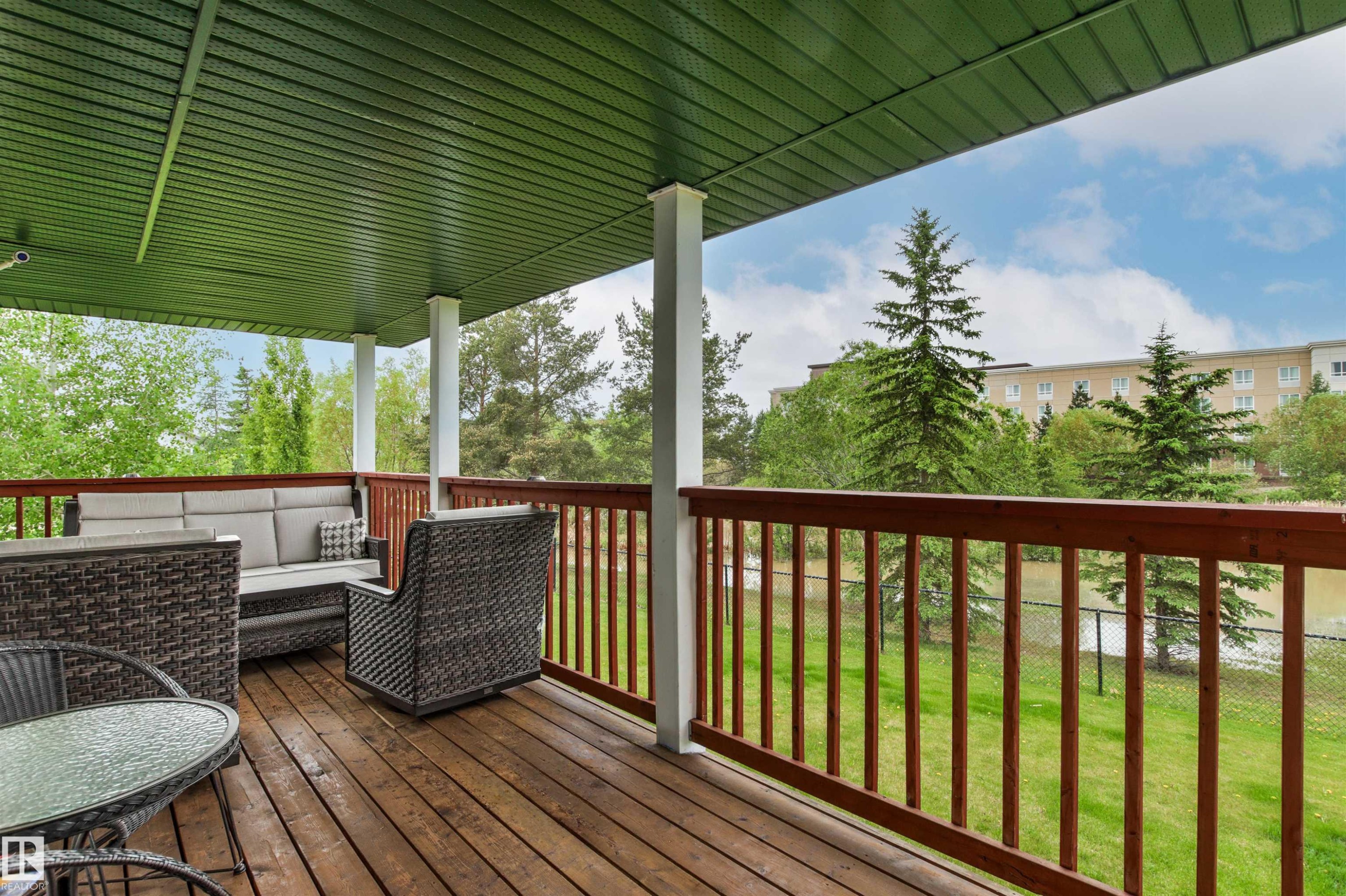 Covered outdoor deck with wood-finish flooring and a wood railing - 32 Lamplight Bay, Spruce Grove, AB