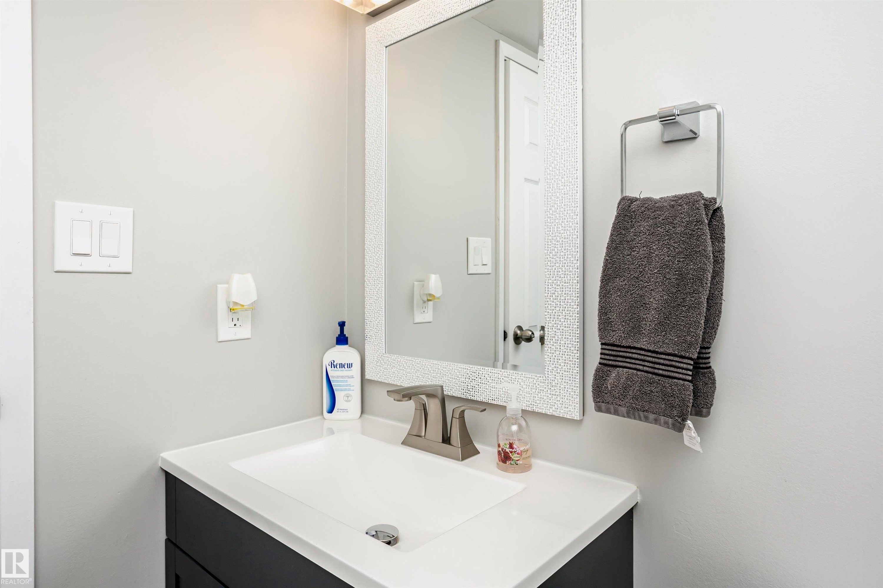 Bathroom vanity featuring a white countertop, undermount sink, and brushed nickel faucet - 3103 109 Street, Edmonton, AB