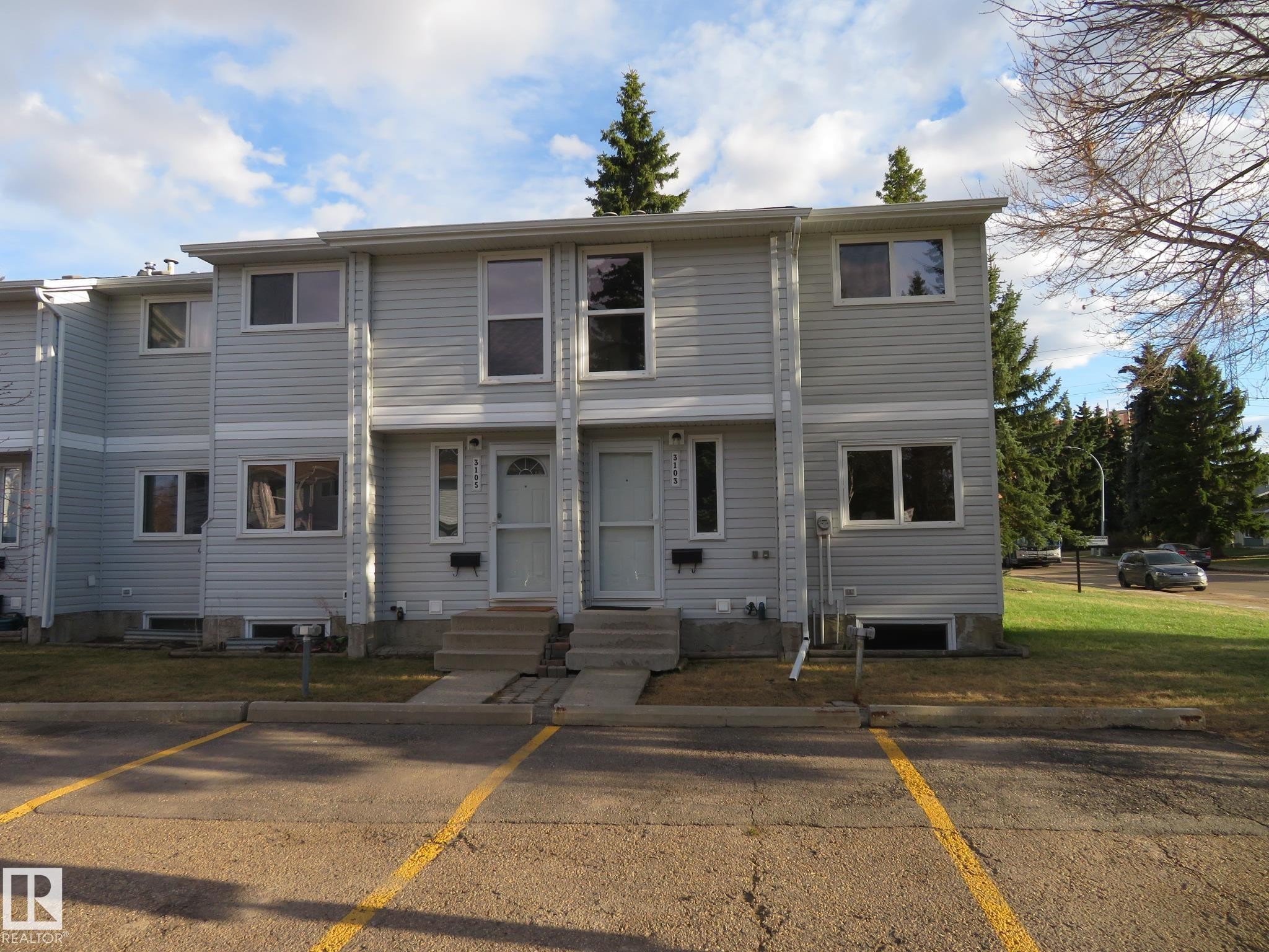 Multi-unit property featuring light-gray horizontal siding, white trim windows, and two distinct entrances with white screen doors - 3103 109 Street, Edmonton, AB