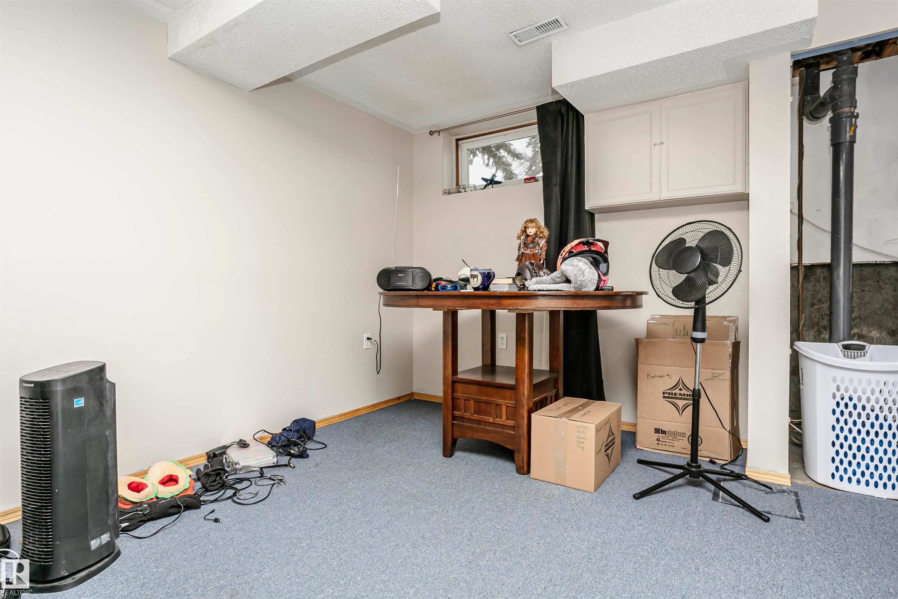 Finished room featuring blue carpeting, a white painted wall, and a horizontal window with a dark curtain - 3103 109 Street, Edmonton, AB