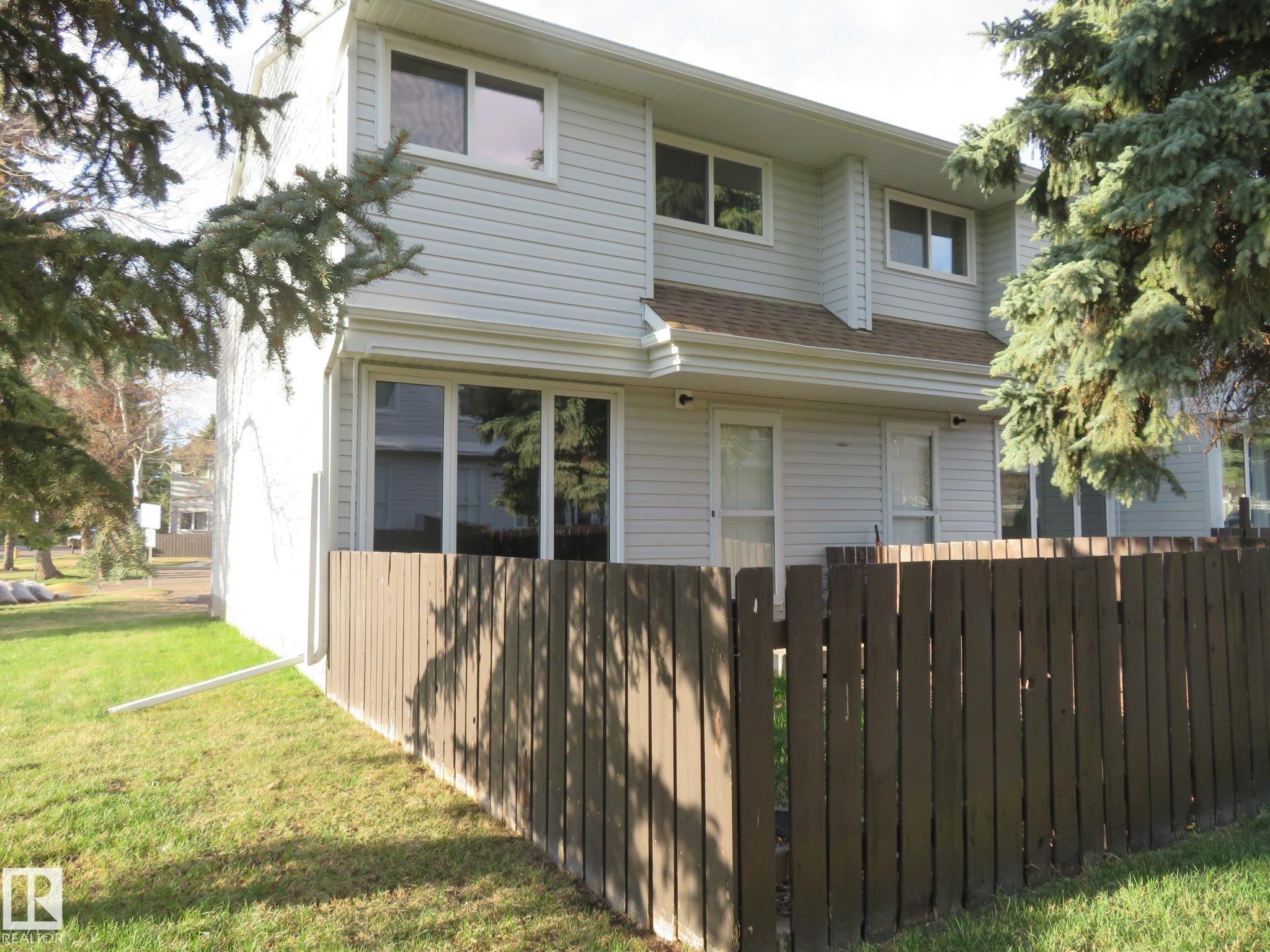 Two-story property featuring light-colored siding, a brown shingle roof, and multiple windows - 3103 109 Street, Edmonton, AB