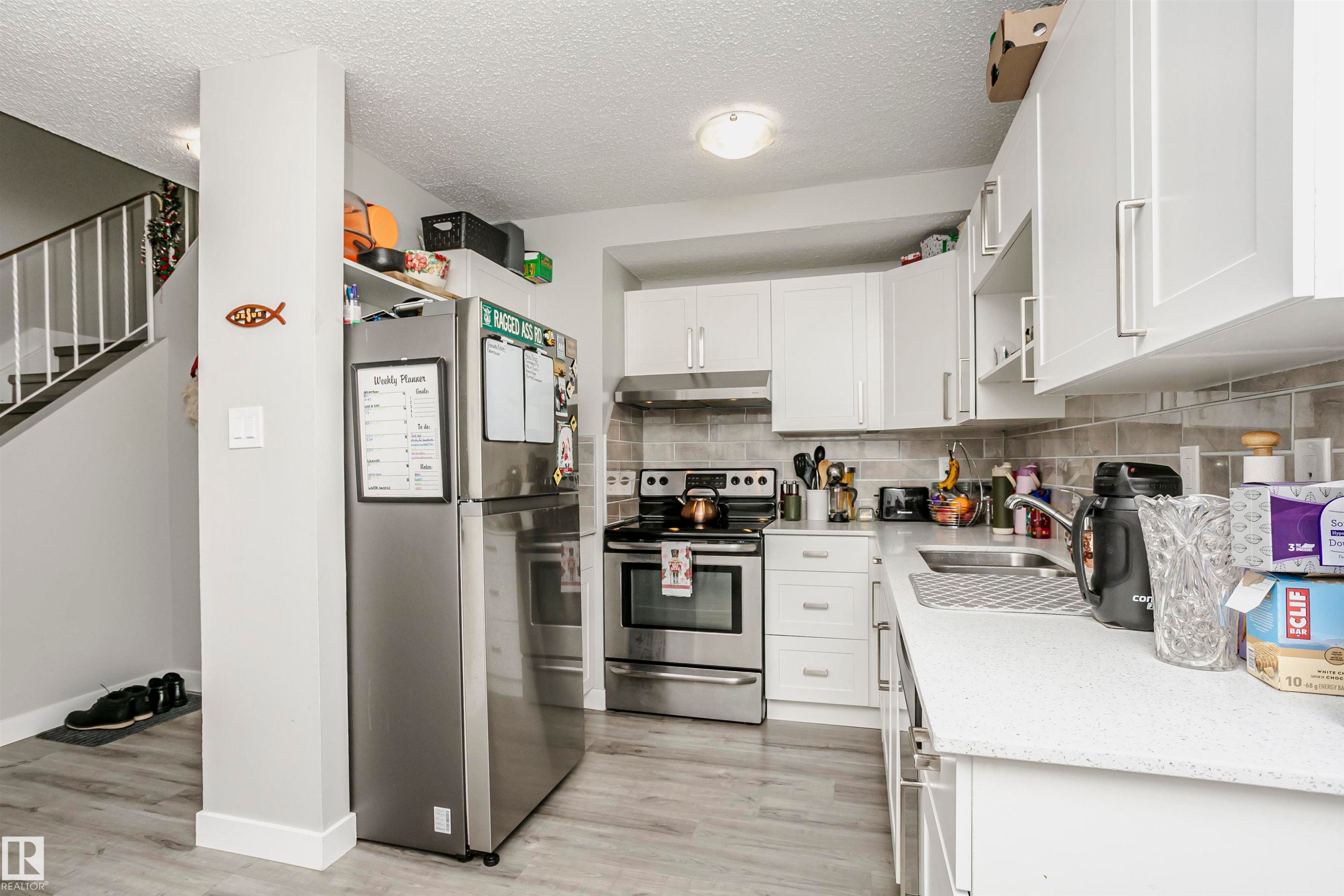 Modern kitchen featuring white cabinetry, a stainless steel electric range, and a dual-basin sink - 3103 109 Street, Edmonton, AB
