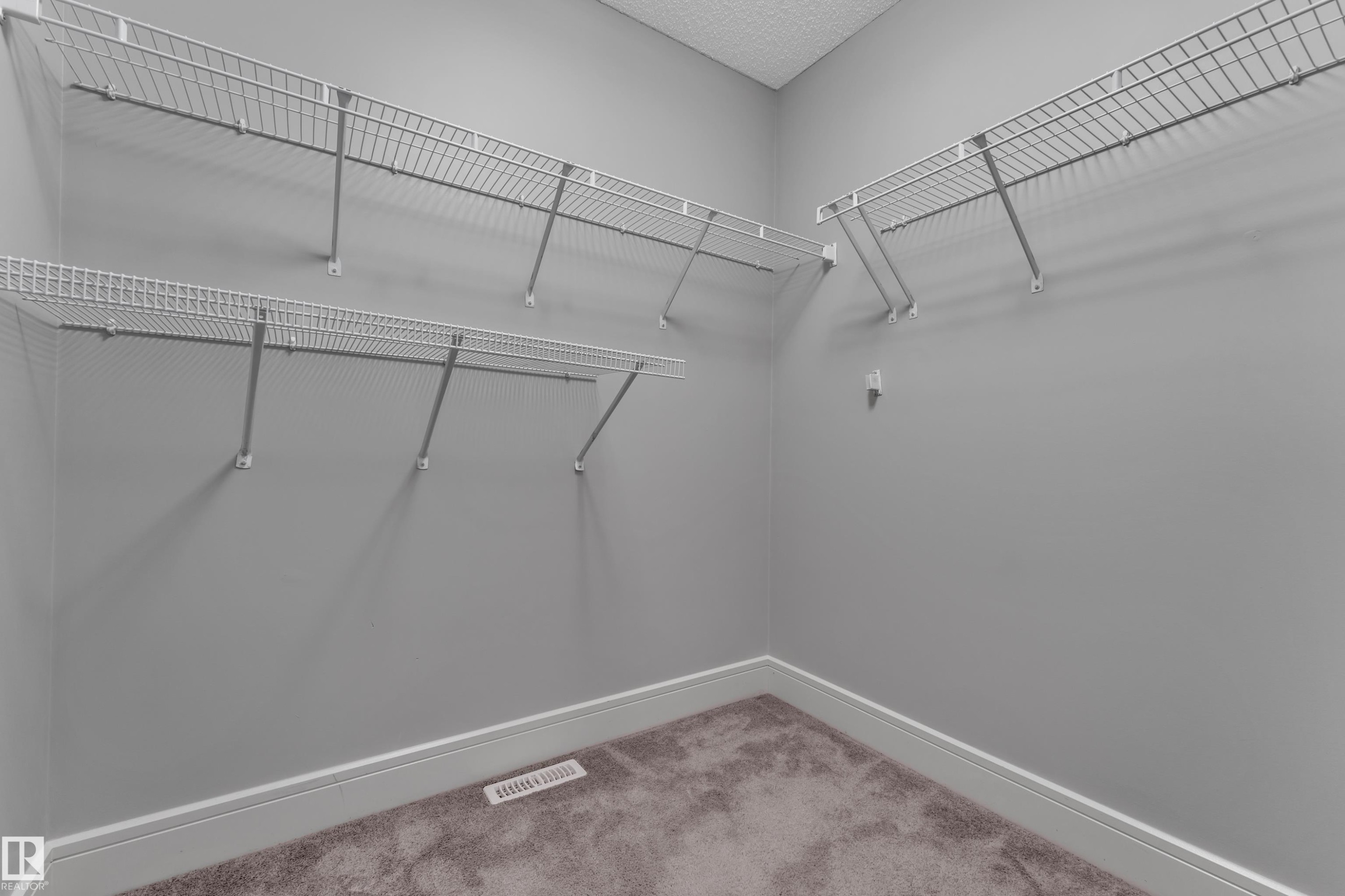 Walk-in closet featuring wire shelving, gray painted walls, white baseboards, and brown carpet flooring - 3363 13 Ave, Edmonton, AB