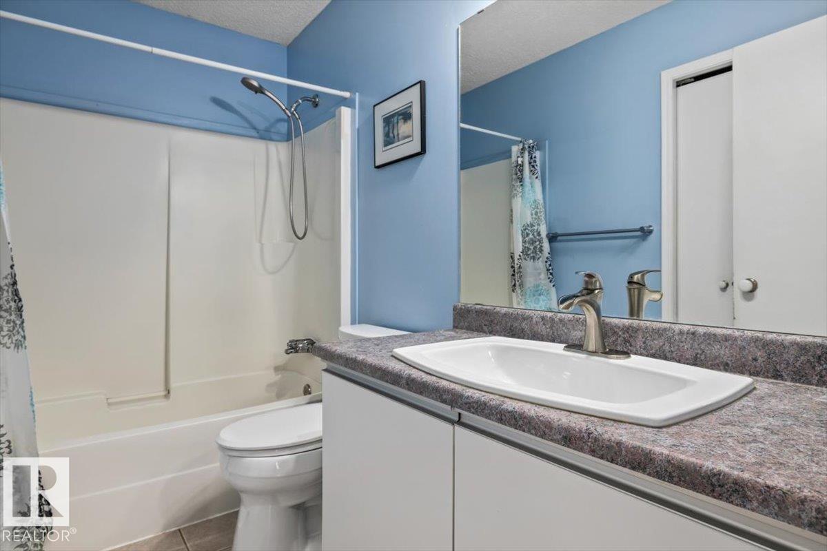 Bathroom featuring a white vanity with integrated sink, patterned countertop, and a large wall-mounted mirror - 8103 154 Avenue, Edmonton, AB
