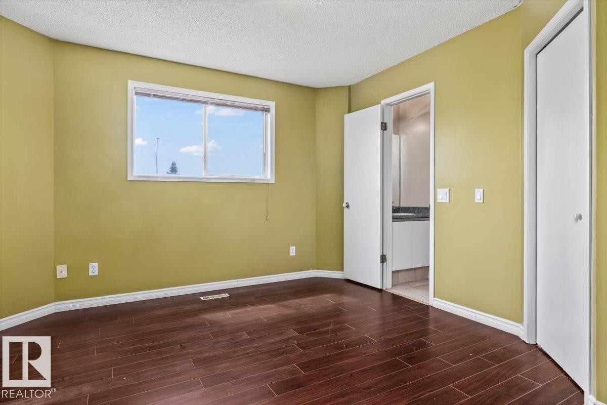 Room featuring wood-finish flooring, a bright window, and a crisp white ceiling - 8103 154 Avenue, Edmonton, AB
