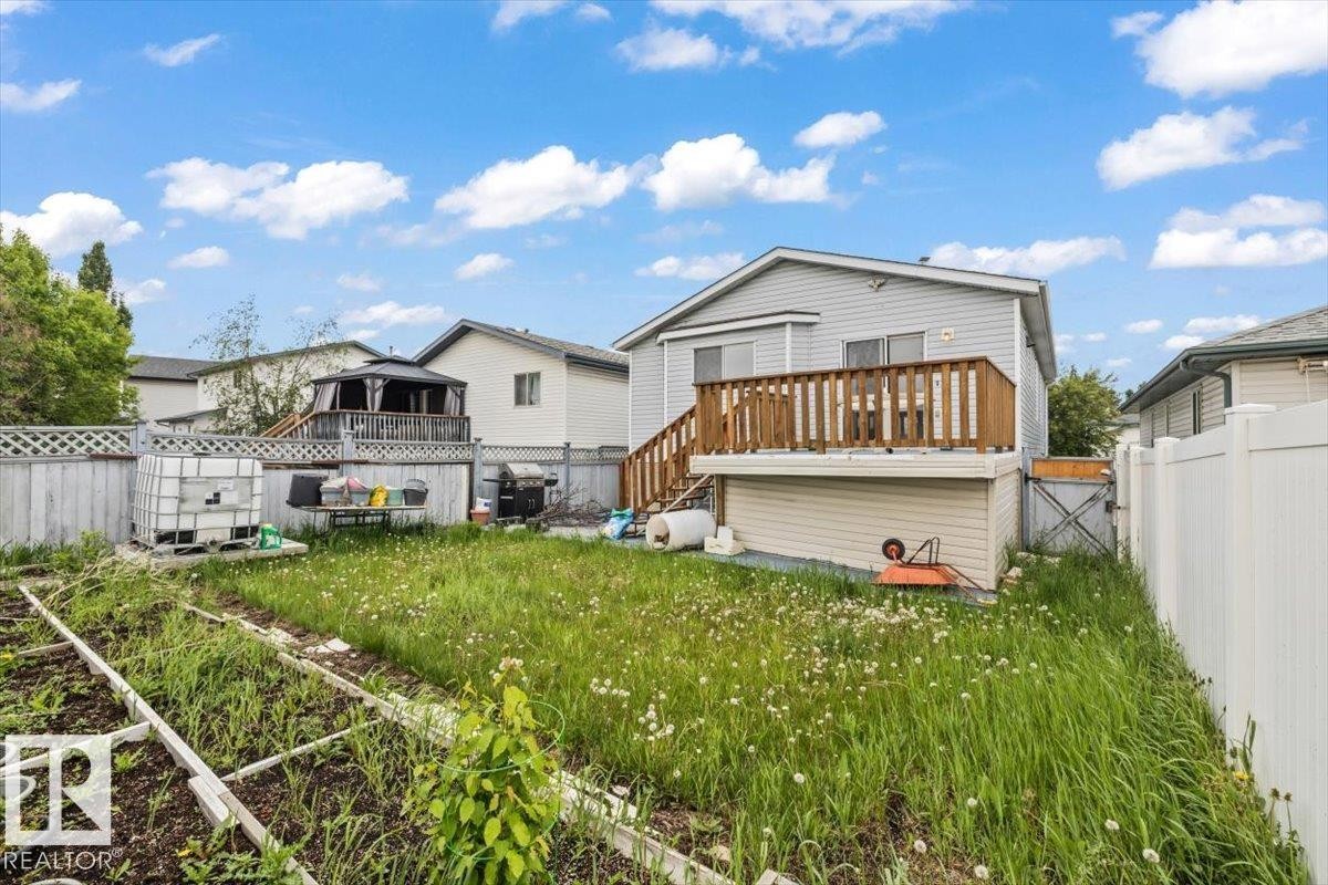 Rear exterior featuring a wood deck with railing, siding facade, and a fenced yard - 8103 154 Avenue, Edmonton, AB