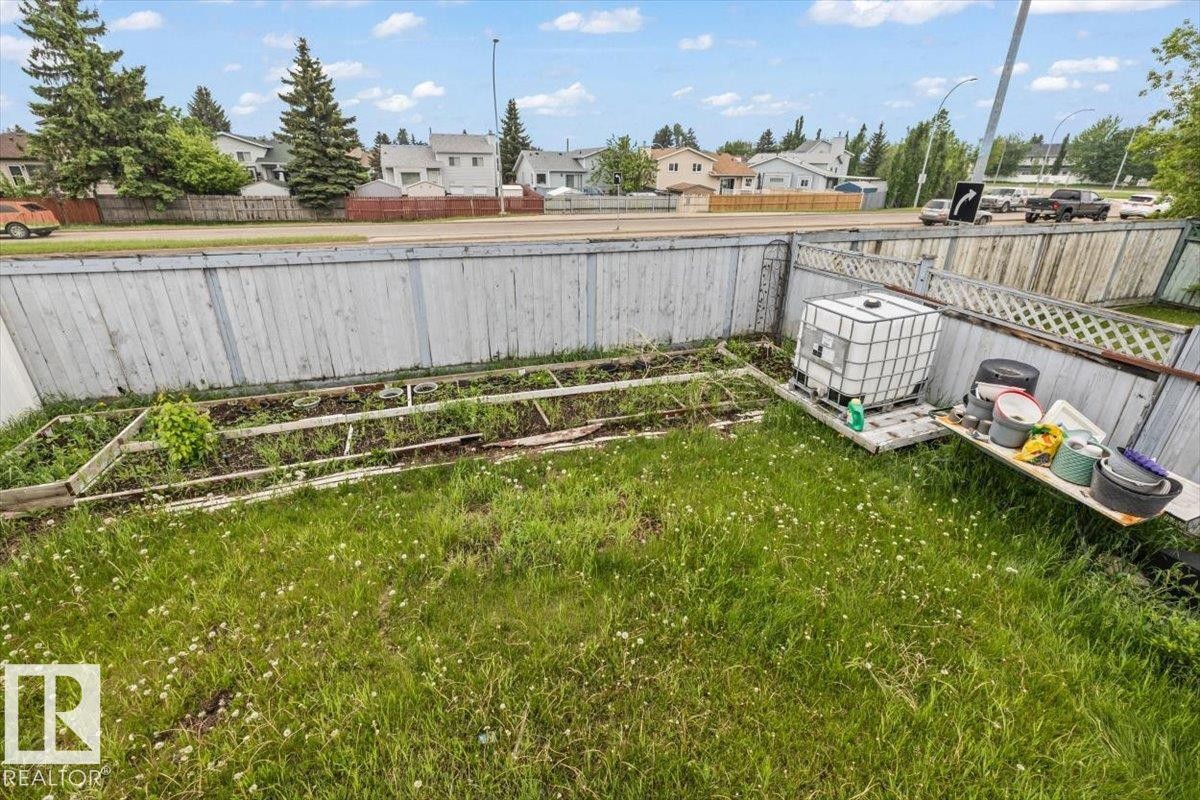 Fenced backyard with established garden beds and a grassy area - 8103 154 Avenue, Edmonton, AB