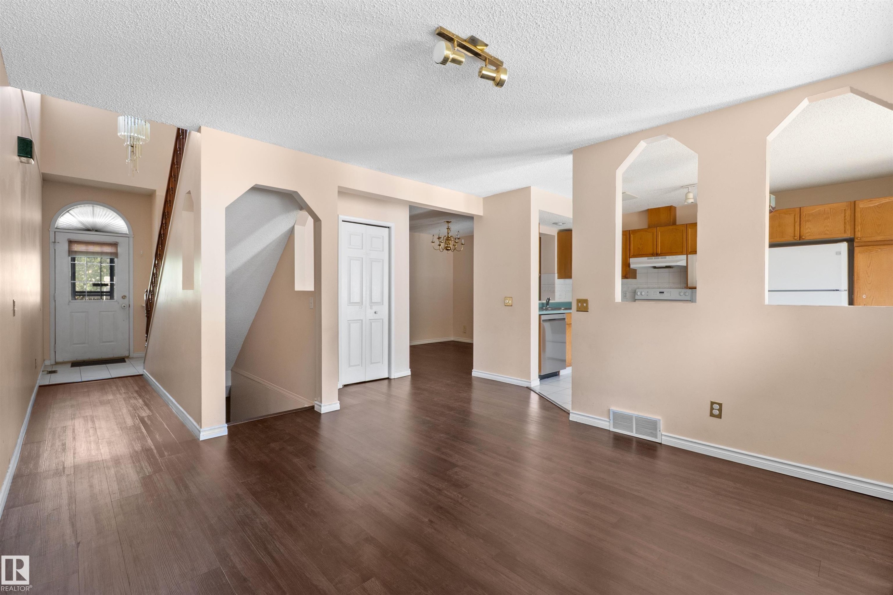 Spacious living area featuring wood-finish flooring, a neutral color palette, and multiple arched wall openings - 5 20 Deerbourne Drive, St. Albert, AB