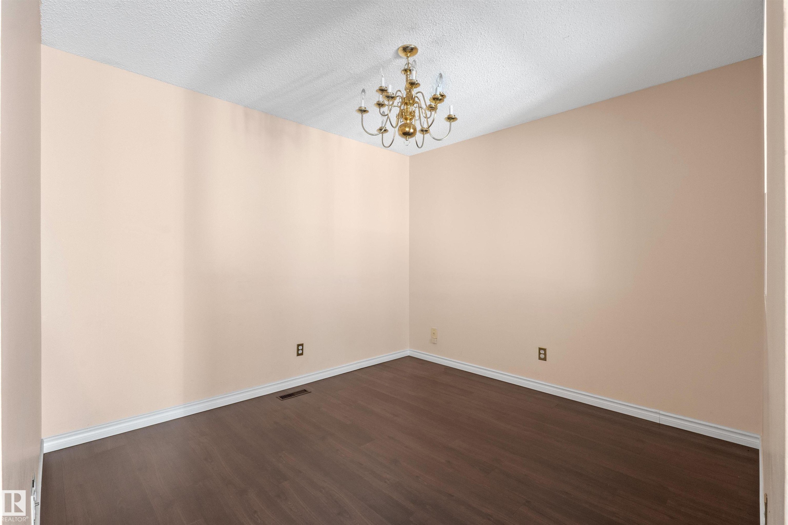 Spacious room featuring wood-finish flooring, light-toned walls, white baseboards, and a brass chandelier - 5 20 Deerbourne Drive, St. Albert, AB