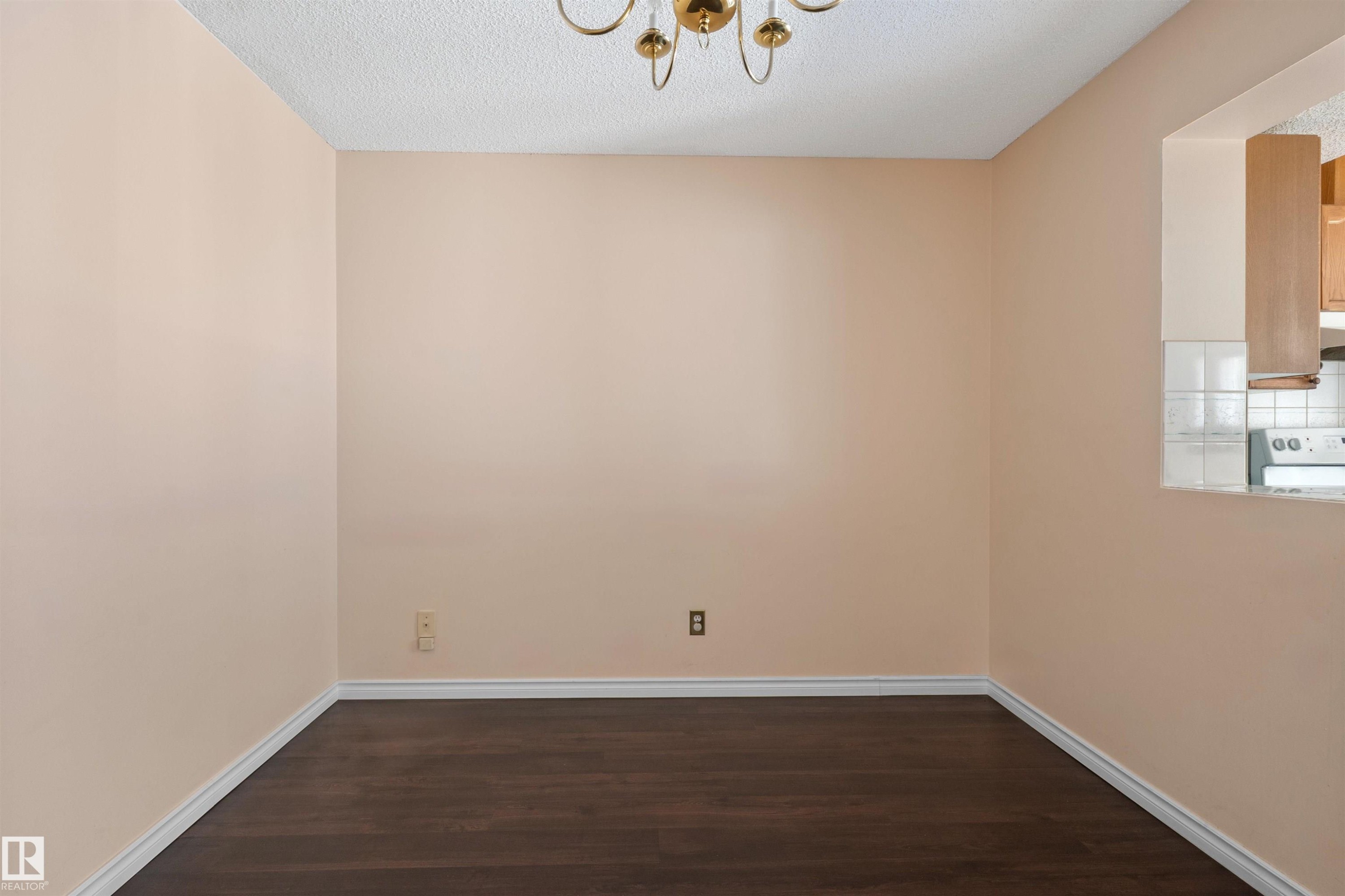 Spacious interior room featuring wood-finish flooring and light-toned walls - 5 20 Deerbourne Drive, St. Albert, AB