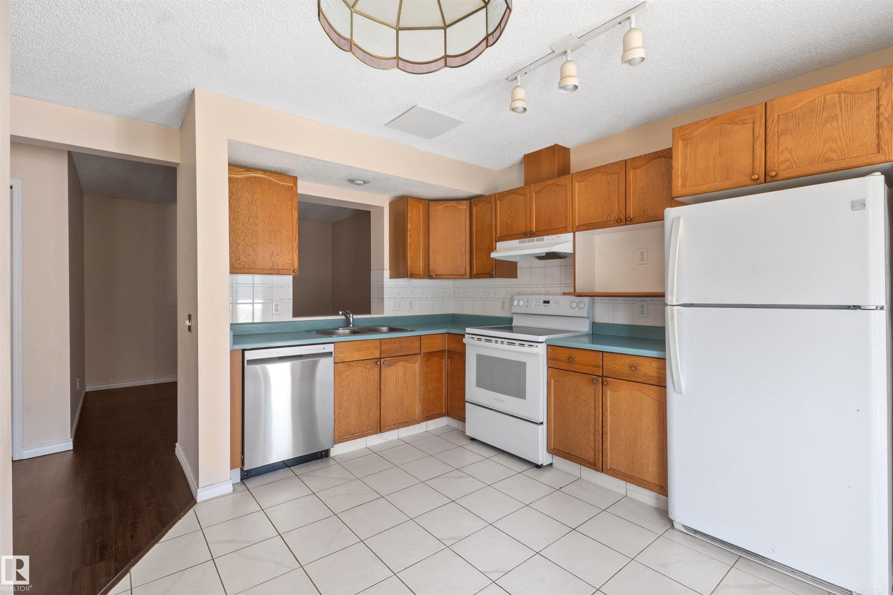U-shaped kitchen featuring wood-finish cabinetry and light blue countertops - 5 20 Deerbourne Drive, St. Albert, AB