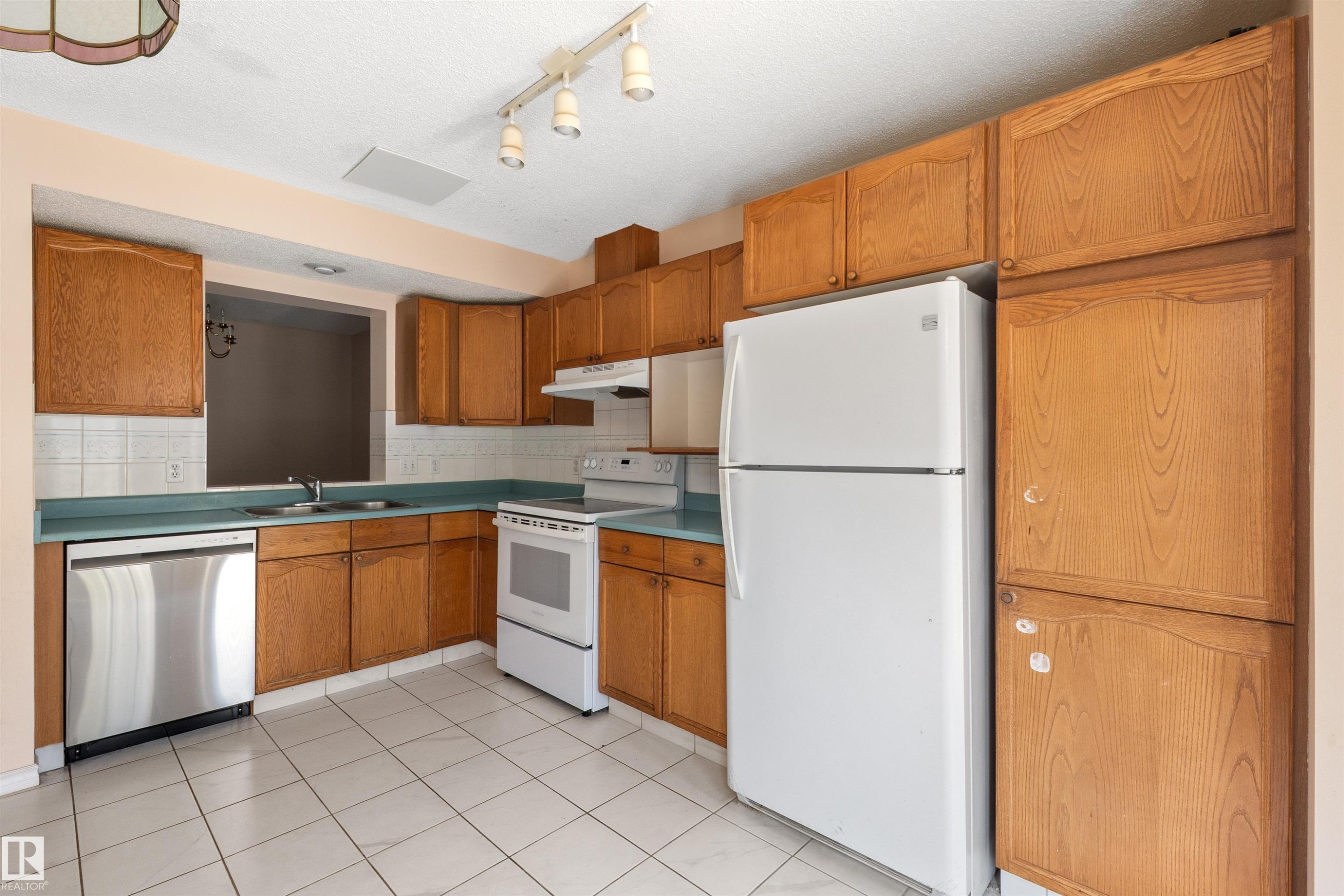 Kitchen featuring light wood cabinetry, white tile flooring, and a stainless steel dishwasher - 5 20 Deerbourne Drive, St. Albert, AB