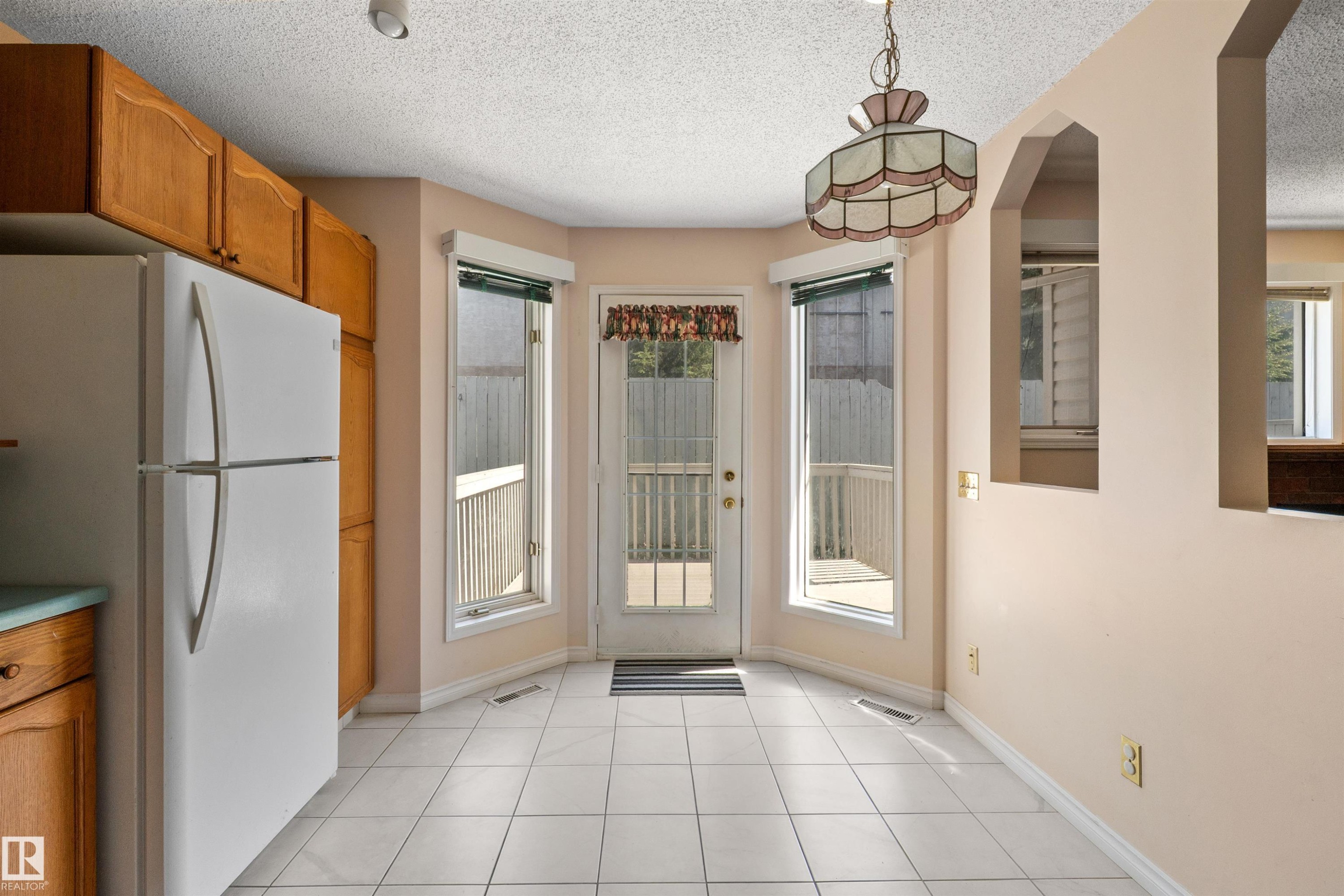 Bright kitchen space featuring wood cabinetry and white tiled flooring - 5 20 Deerbourne Drive, St. Albert, AB