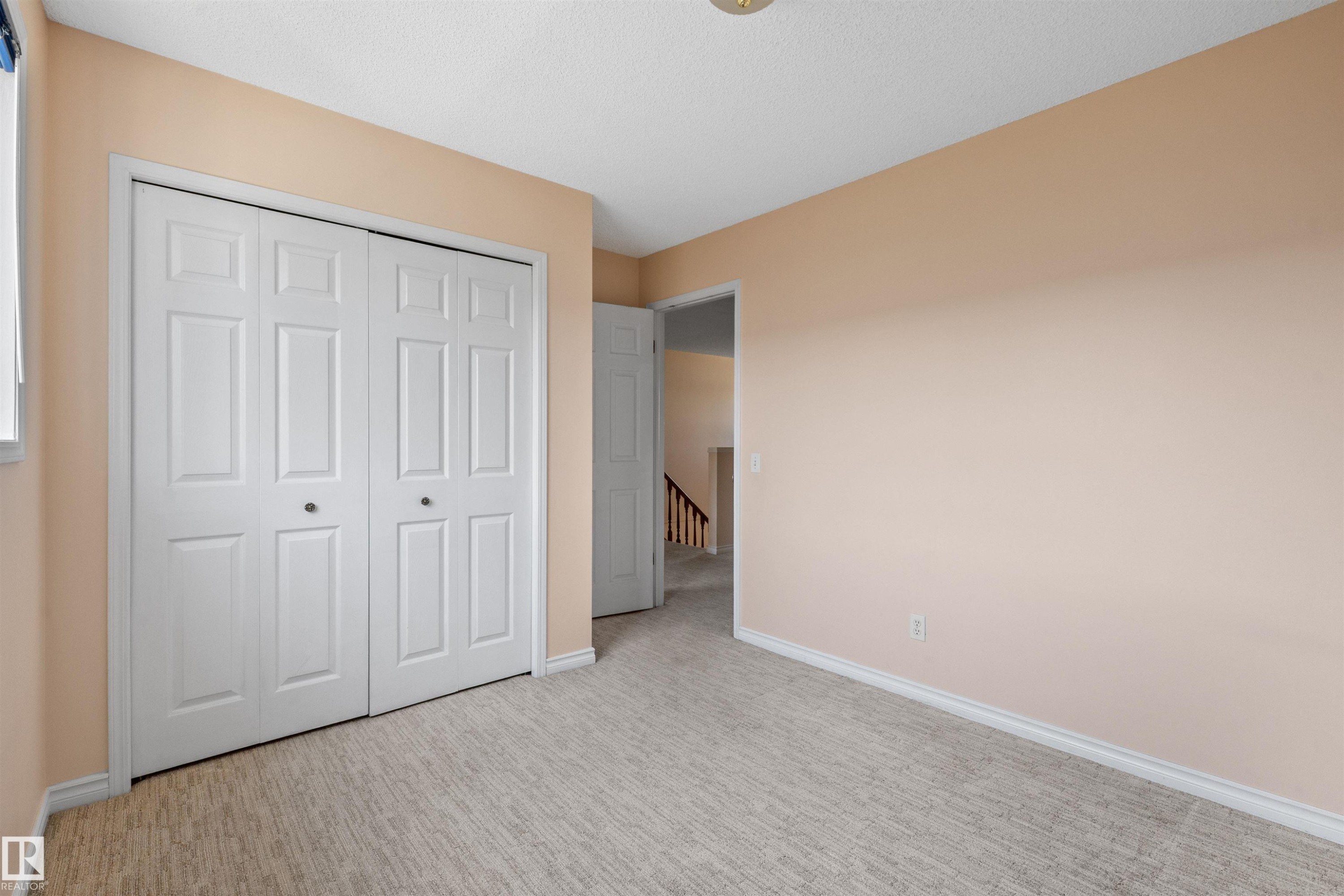 Room featuring bifold closet doors, light-colored walls, and textured carpeting - 5 20 Deerbourne Drive, St. Albert, AB