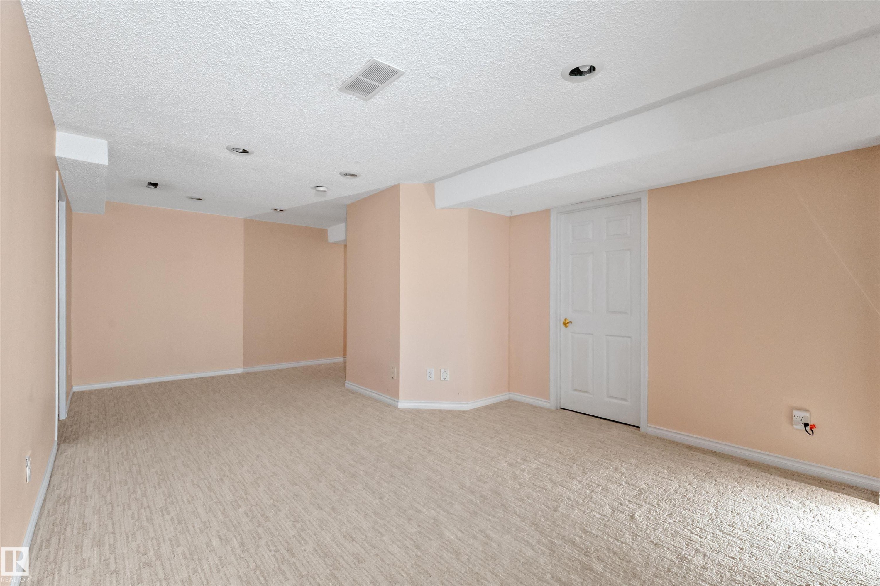 Spacious finished room featuring textured carpeting, neutral wall colors, recessed ceiling lighting, and a paneled door - 5 20 Deerbourne Drive, St. Albert, AB