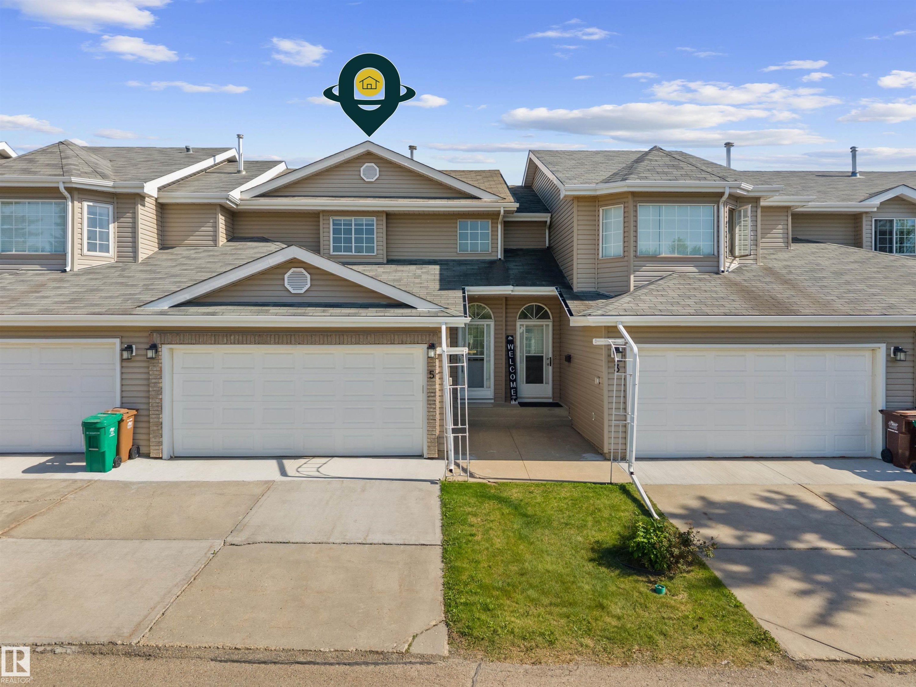 Townhome exterior featuring tan siding, a gabled roofline, and multiple windows - 5 20 Deerbourne Drive, St. Albert, AB