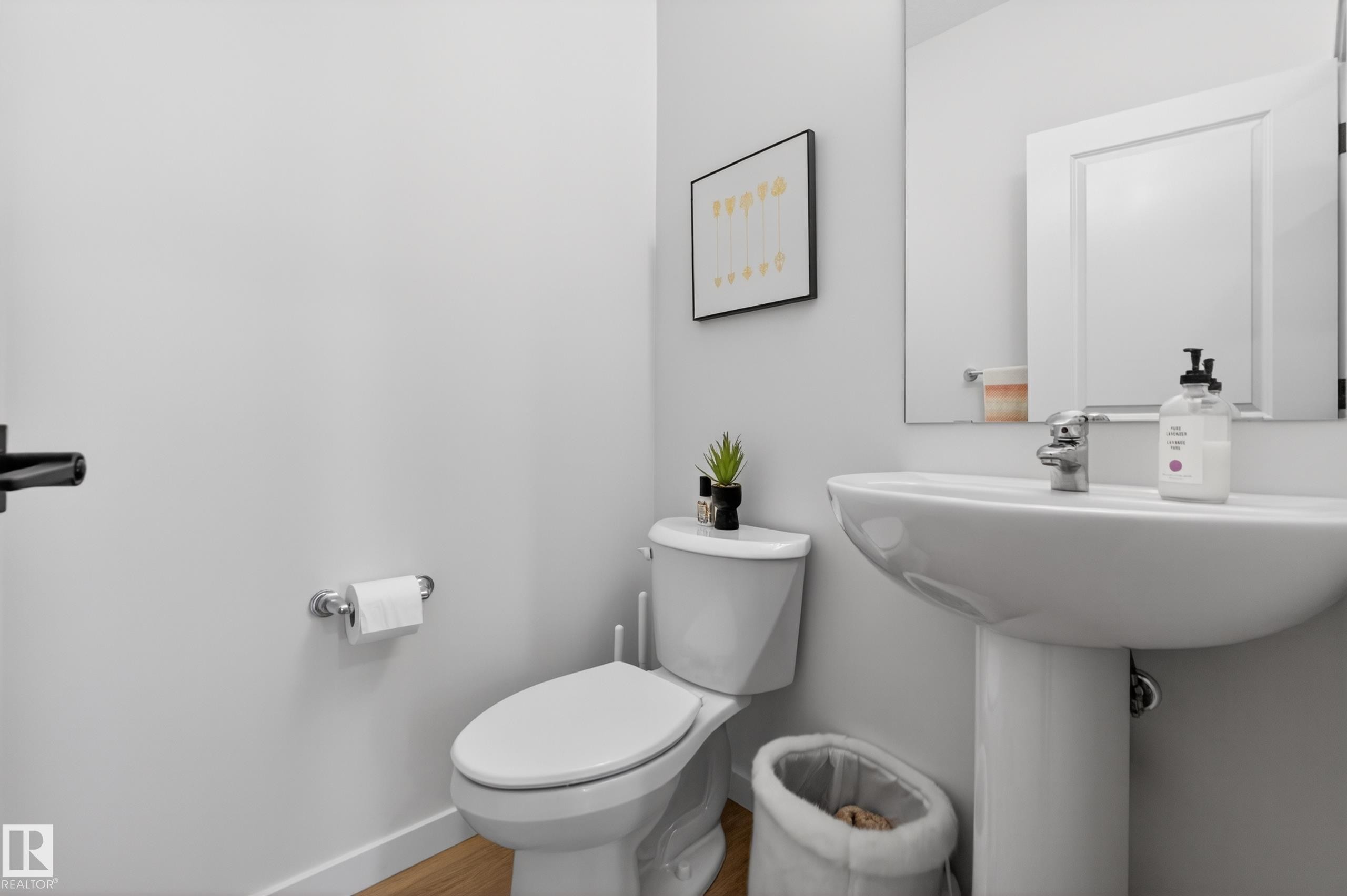Pedestal sink with chrome faucet, complemented by a white toilet and a framed mirror - 17023 45 Street, Edmonton, AB