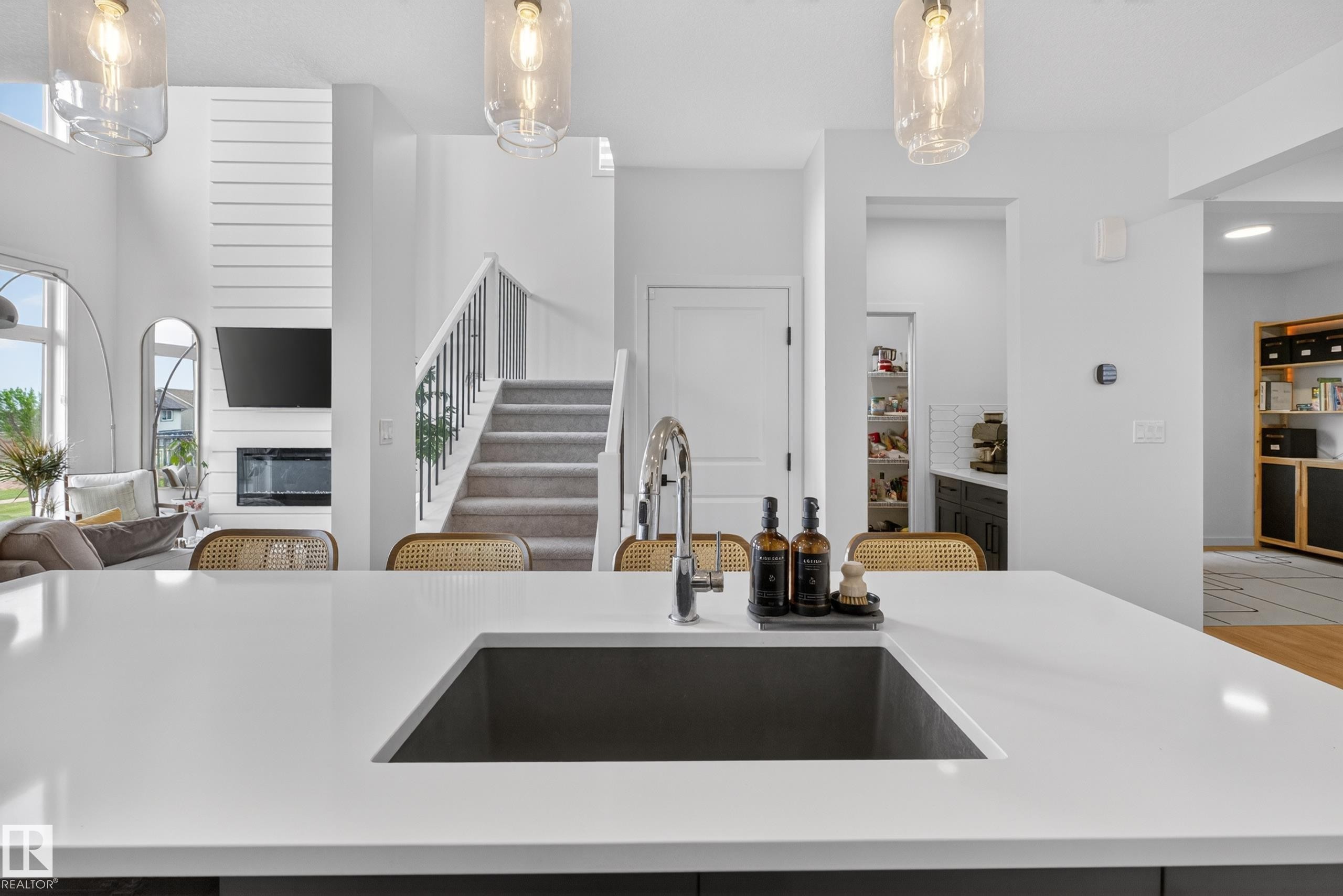 Kitchen island with a dark gray undermount sink, a stainless steel faucet, and a light-toned countertop - 17023 45 Street, Edmonton, AB