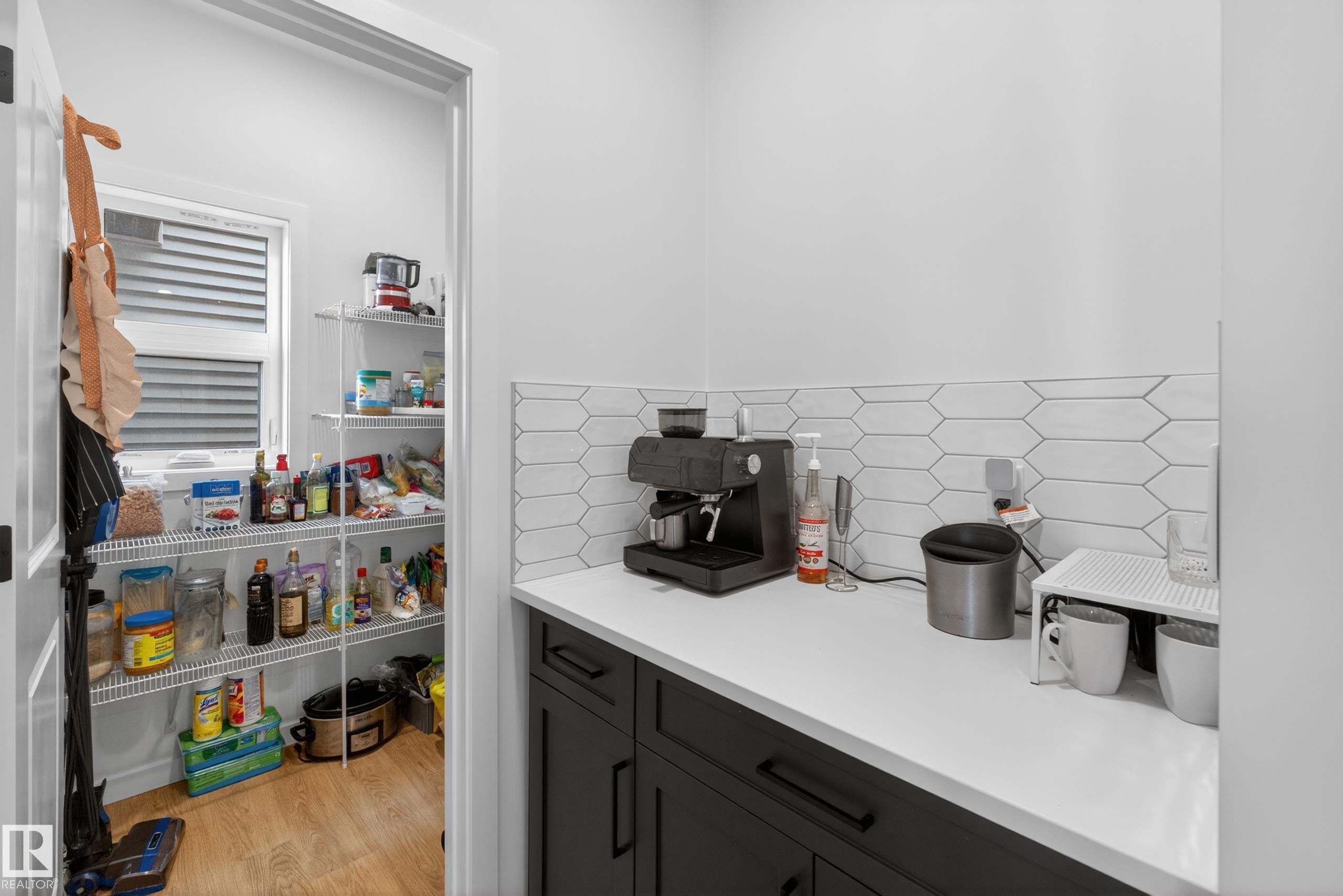 Kitchenette featuring dark-toned base cabinetry, light-toned countertop, and a white picket tile backsplash - 17023 45 Street, Edmonton, AB
