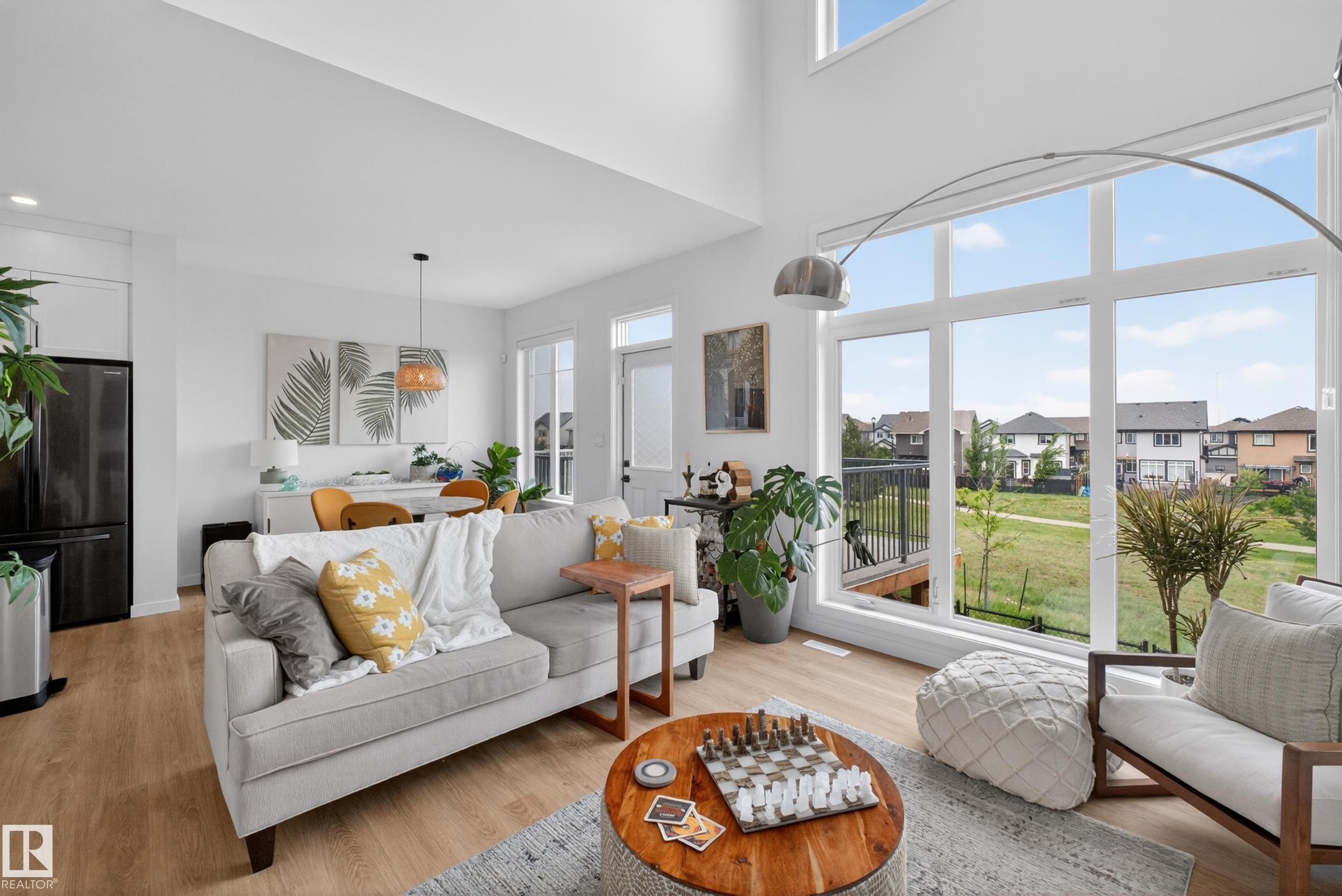Open-concept living area with wood-finish flooring, soaring ceilings, and expansive windows - 17023 45 Street, Edmonton, AB
