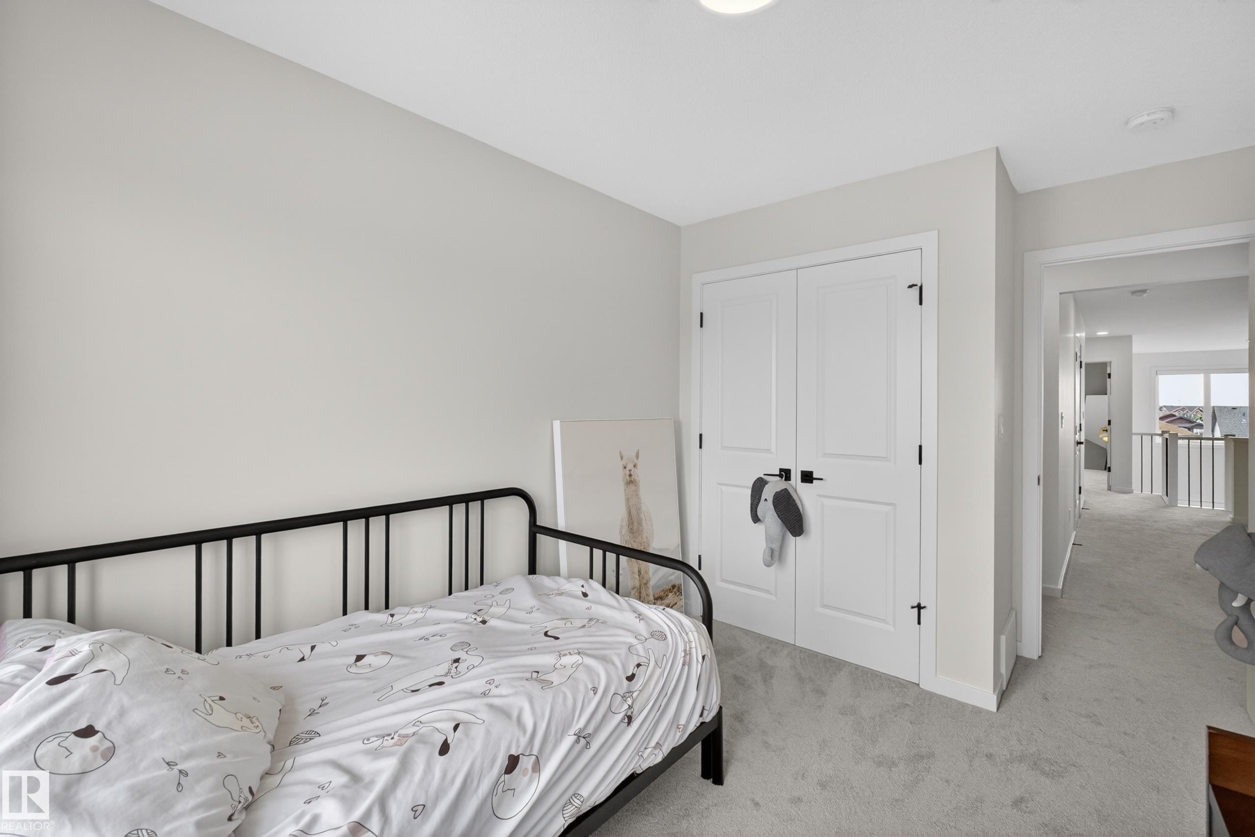 Carpeted bedroom featuring neutral wall tones, a built-in closet with double doors and matte black hardware, and a ceiling-mounted light fixture - 17023 45 Street, Edmonton, AB