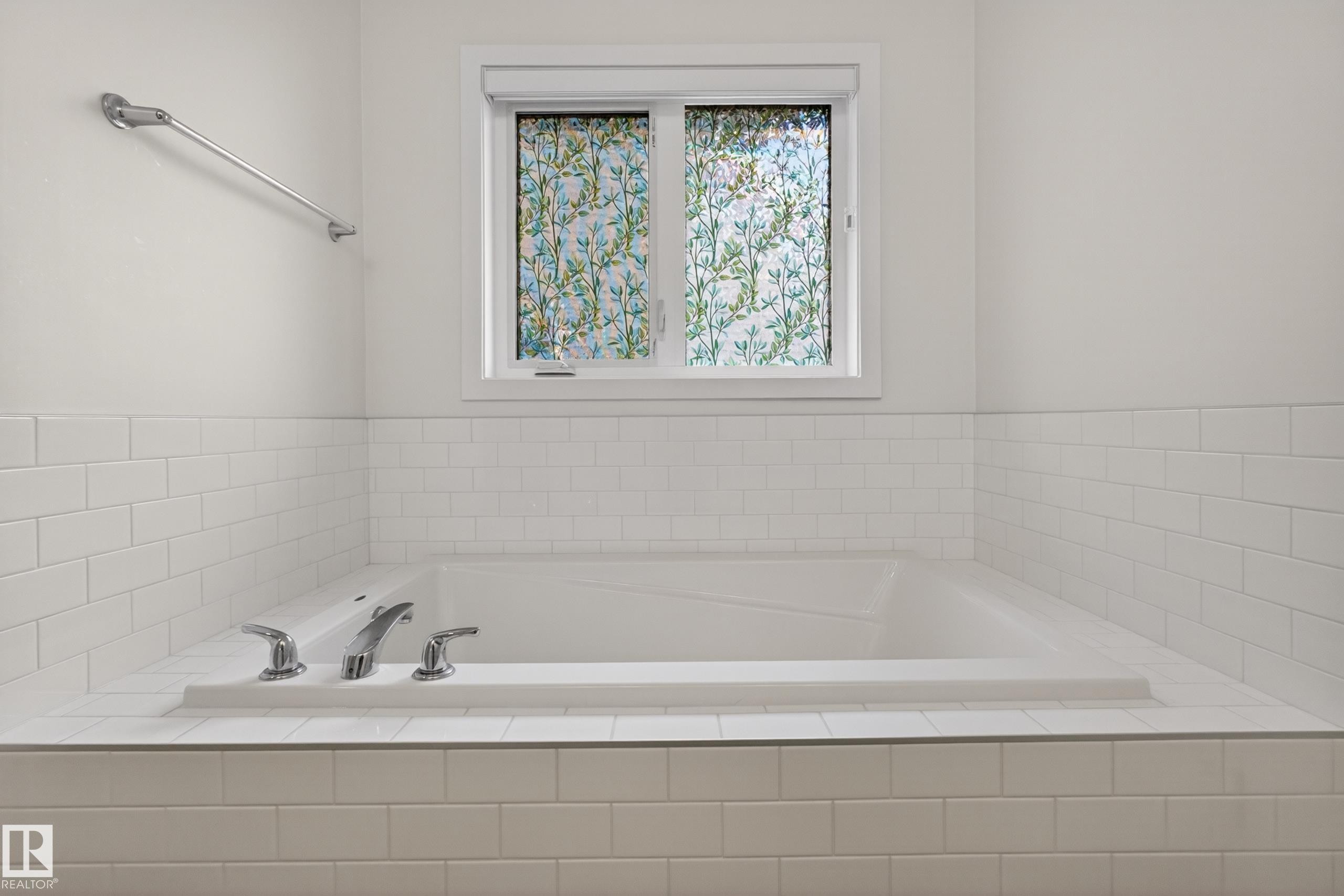Built-in soaking tub featuring subway tile surround, polished chrome fixtures, and an opaque window with decorative film - 17023 45 Street, Edmonton, AB
