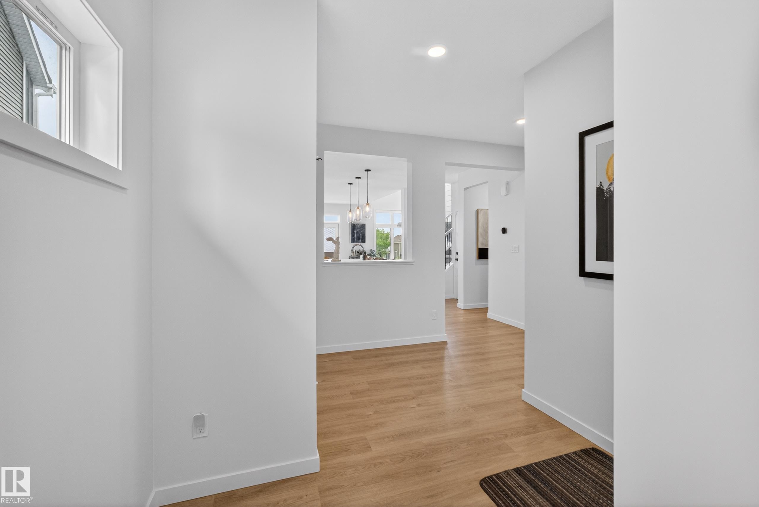 Light wood-finish flooring extending throughout, complemented by white baseboards and neutral wall tones - 17023 45 Street, Edmonton, AB