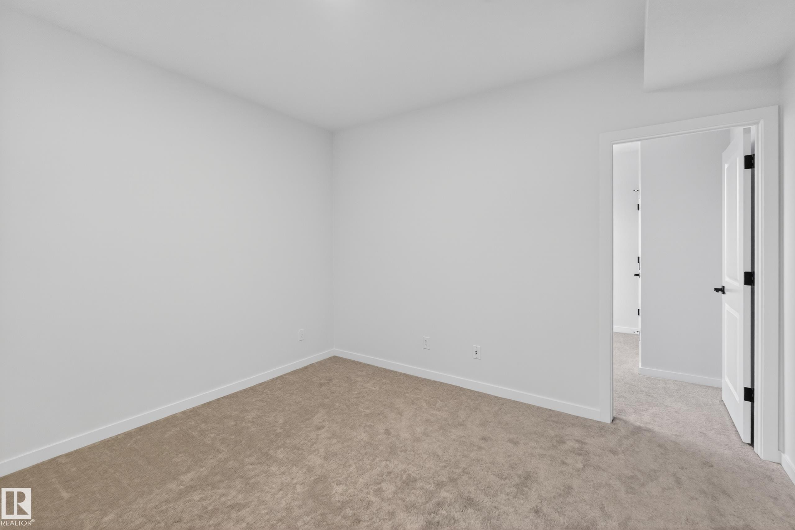 Spacious room featuring neutral carpeting, white baseboards, and bright white walls - 17023 45 Street, Edmonton, AB