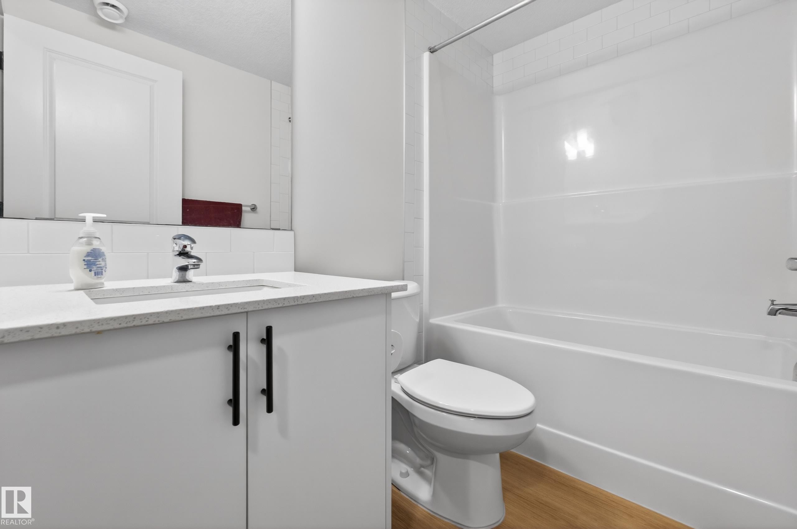 Bathroom featuring a white vanity with black hardware, a light-toned countertop, and a built-in sink - 17023 45 Street, Edmonton, AB