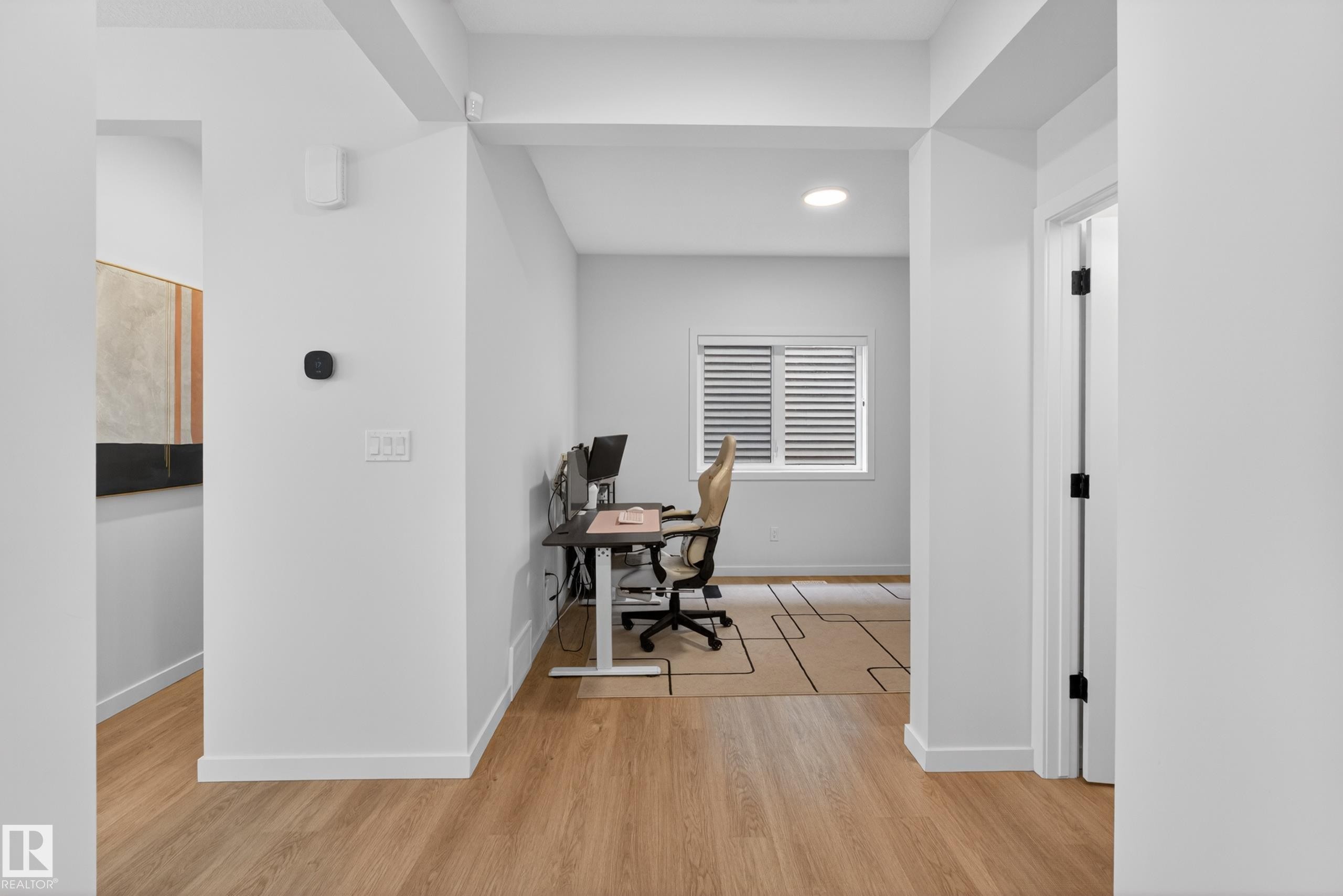 Bright interior space featuring light wood-finish flooring, white walls, recessed lighting, and a window with horizontal blinds - 17023 45 Street, Edmonton, AB