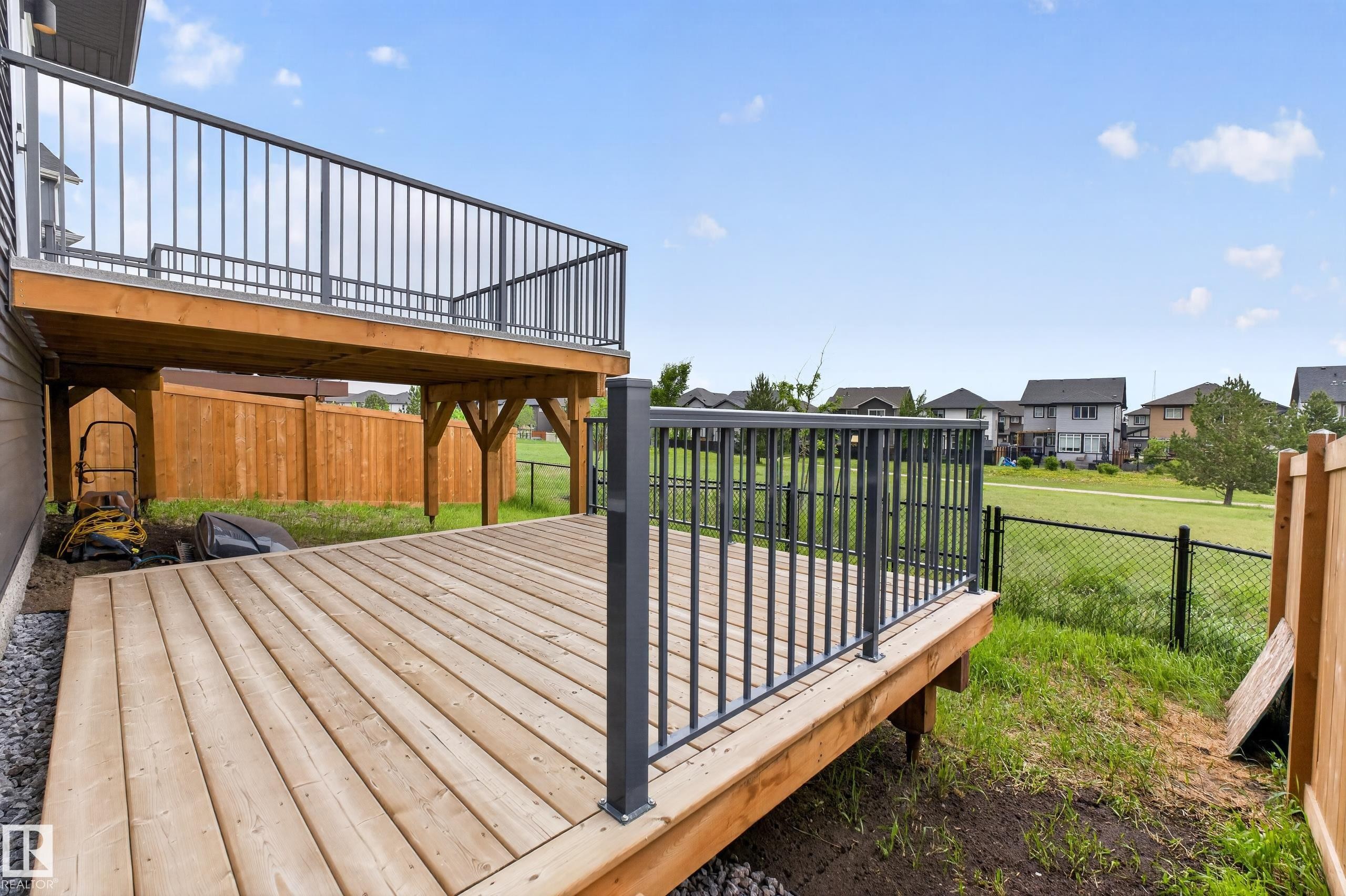 Ground-level wood deck featuring dark gray metal railings and a wood privacy fence - 17023 45 Street, Edmonton, AB
