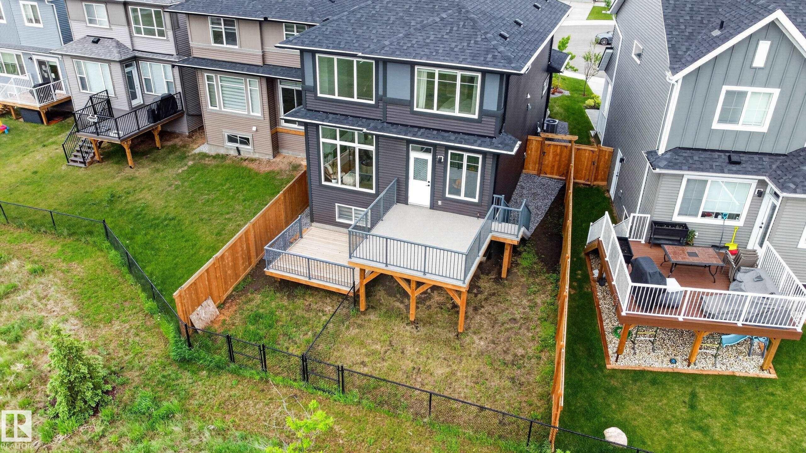 Modern two-story residence featuring a dark gray exterior, a spacious deck with metal railings, and a fenced backyard - 17023 45 Street, Edmonton, AB
