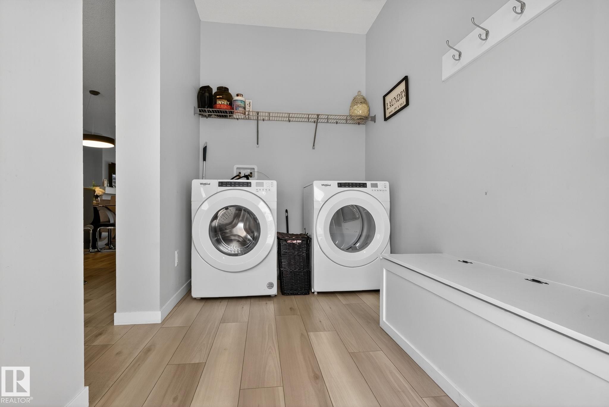Dedicated laundry area featuring wood-finish flooring, light gray walls, a built-in wire shelving unit, and a wall-mounted coat rack - 1213 16A Street, Edmonton, AB
