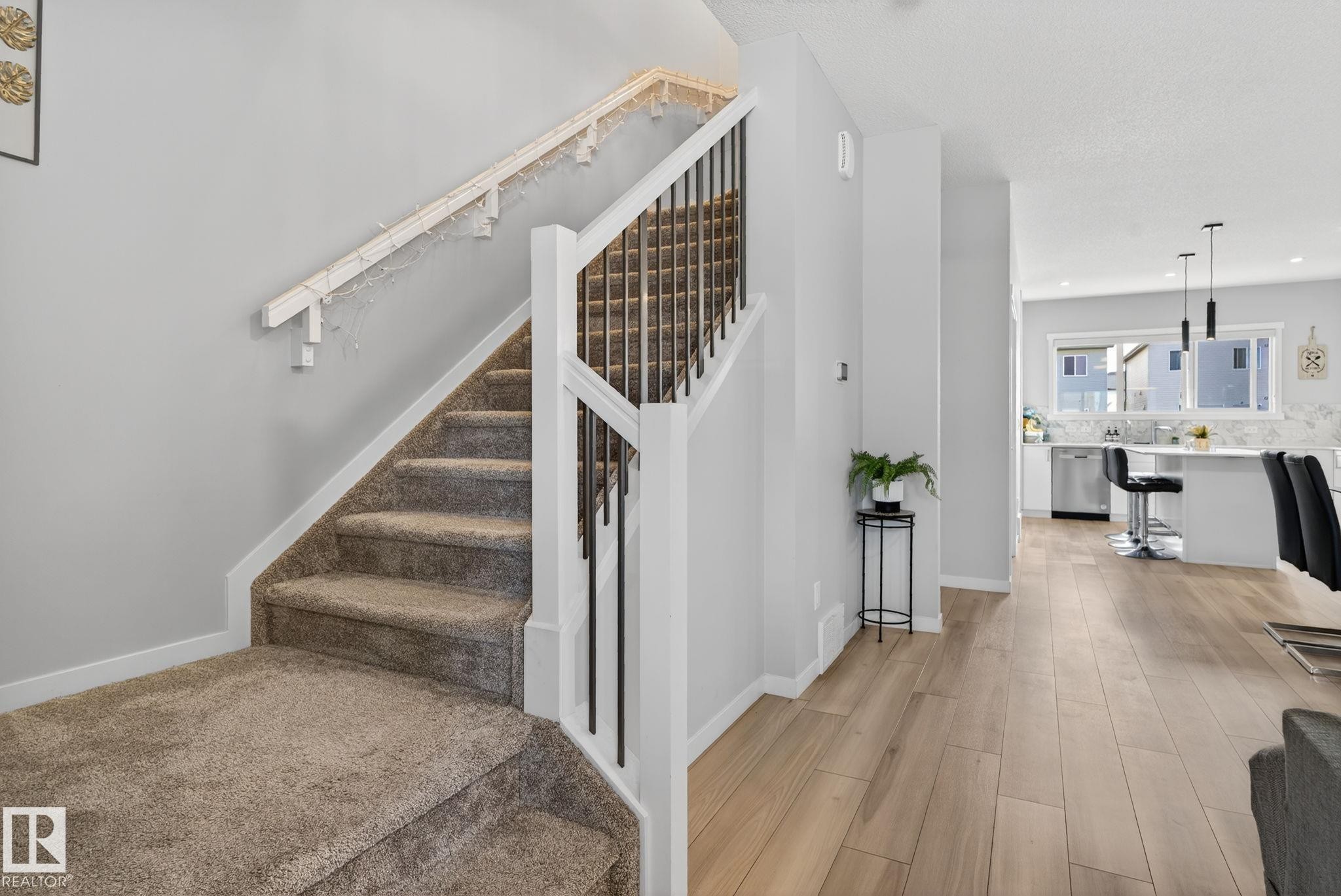 Carpeted staircase with white newel posts and black metal spindles - 1213 16A Street, Edmonton, AB