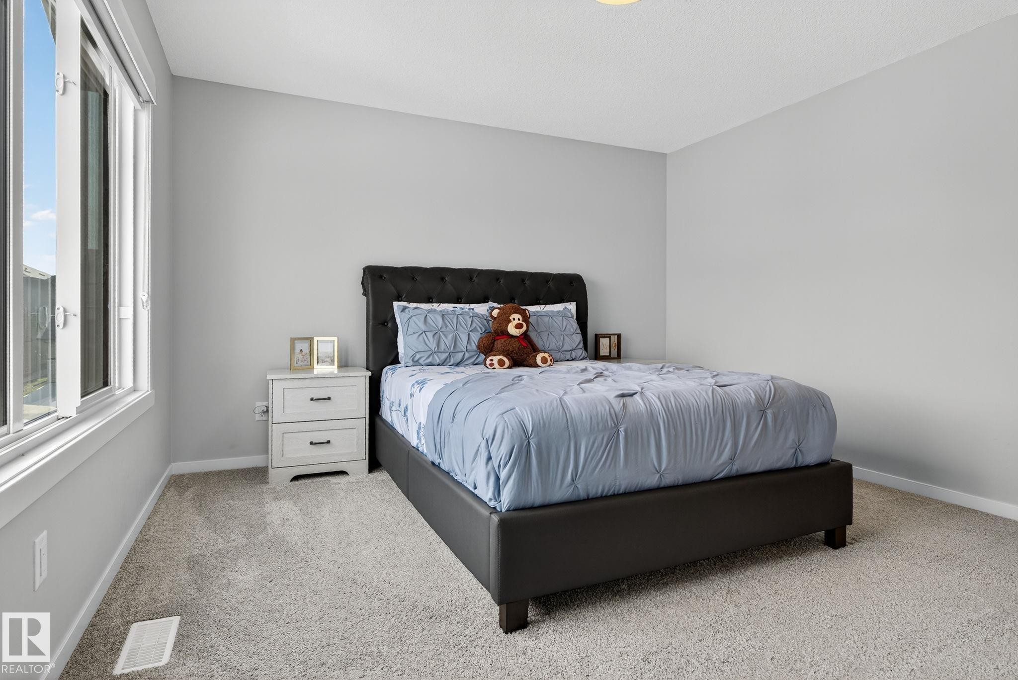 Carpeted room featuring light gray walls, a window with white trim, and a white two-drawer nightstand - 1213 16A Street, Edmonton, AB
