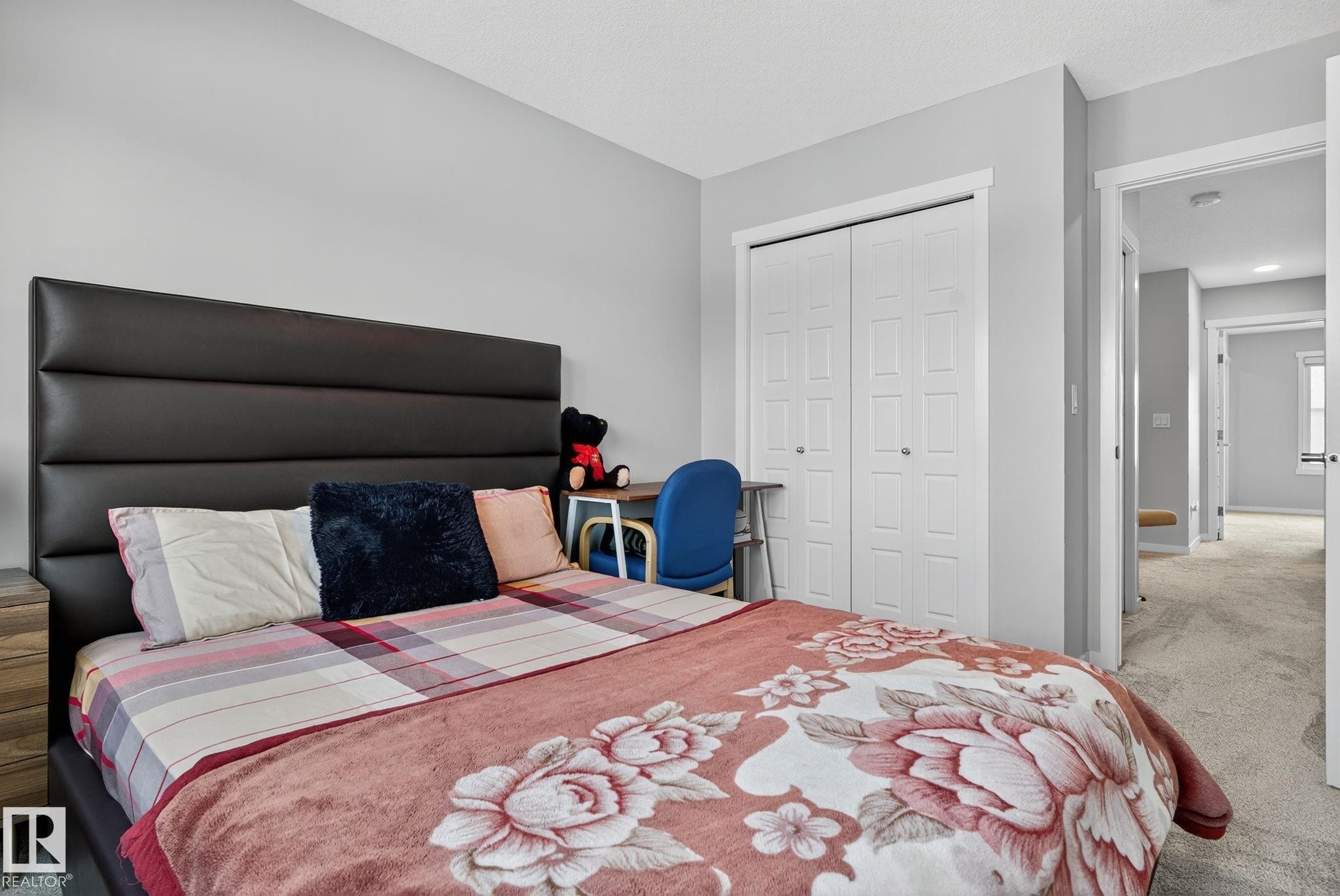 Bedroom featuring light gray walls, plush carpet flooring, and a large closet with bi-fold doors - 1213 16A Street, Edmonton, AB