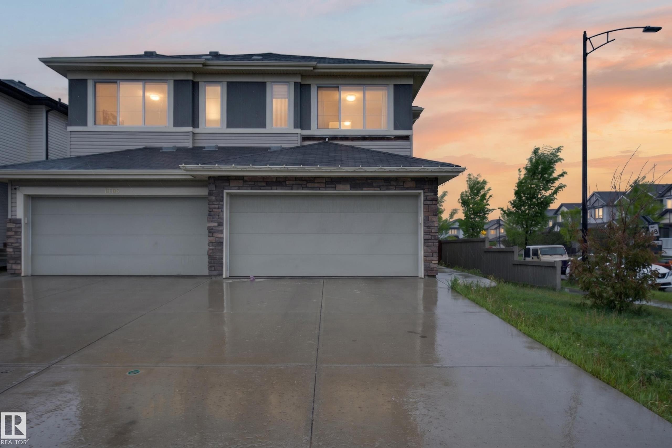 Contemporary residential exterior featuring a two-car garage, stone veneer accents, light gray siding, and a concrete driveway - 1404 25 Avenue, Edmonton, AB