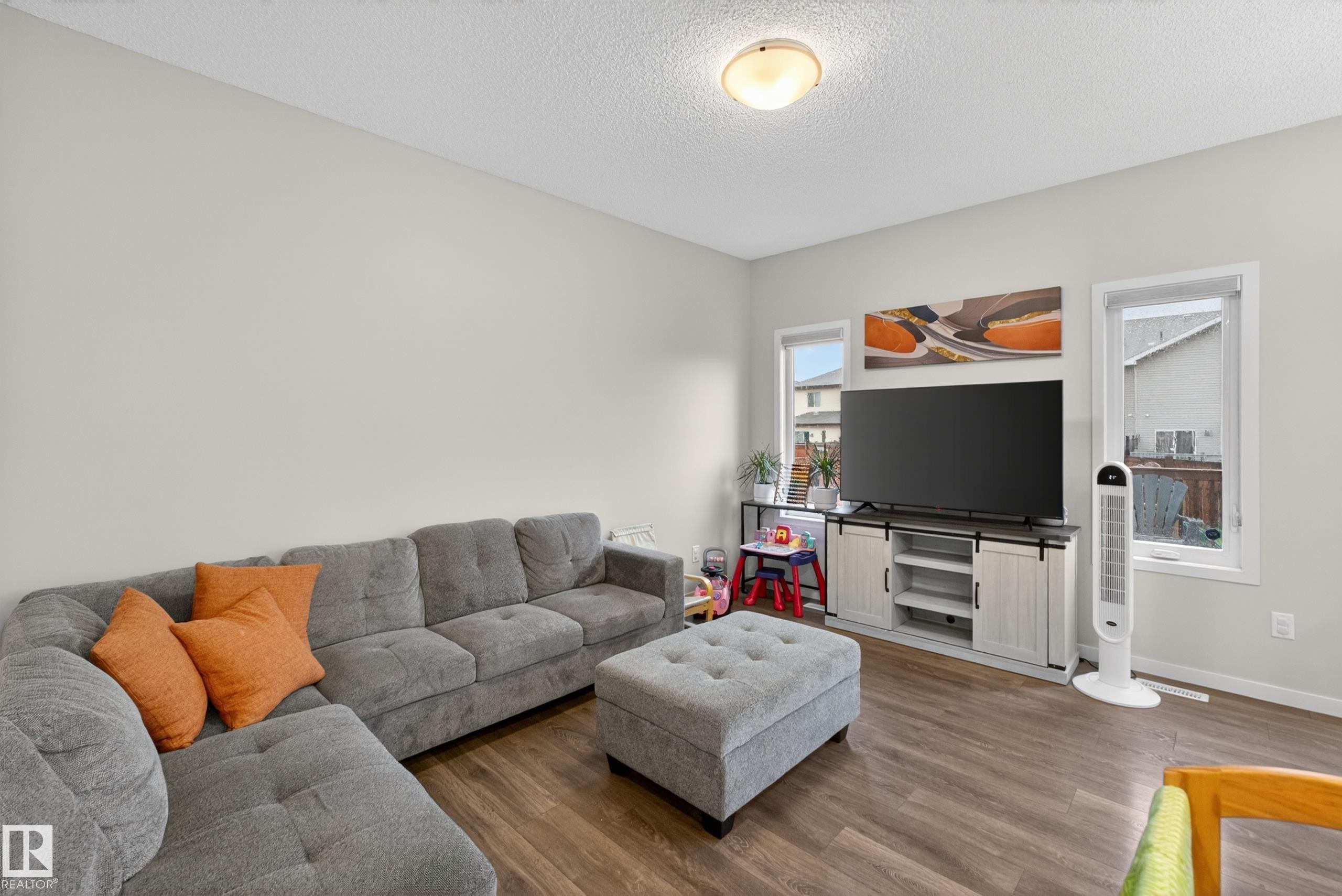 Living area featuring wood-finish flooring, light-colored walls, recessed lighting, and multiple windows providing natural illumination - 1404 25 Avenue, Edmonton, AB