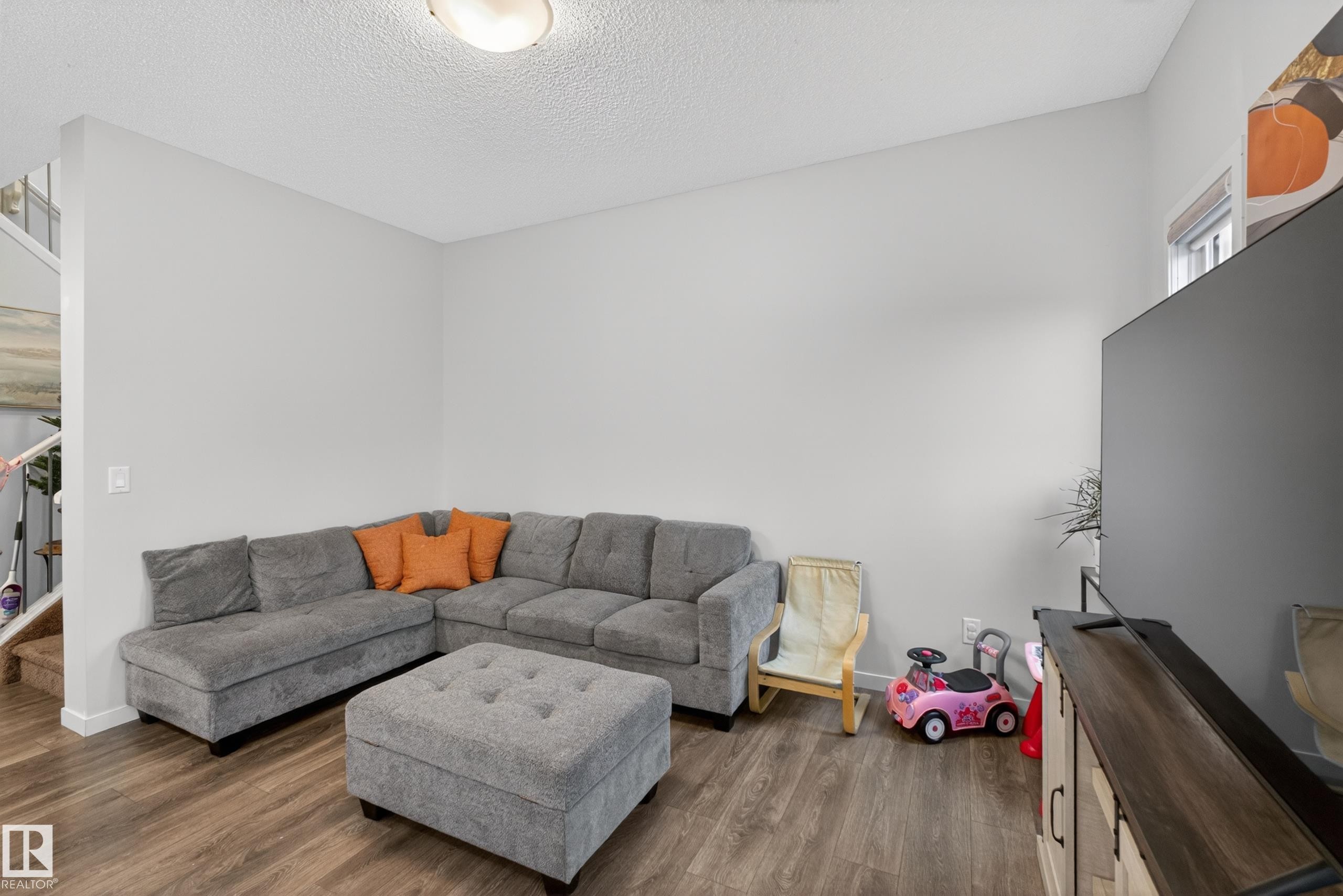 Spacious living area featuring wood-finish flooring, light grey walls, and a high ceiling - 1404 25 Avenue, Edmonton, AB